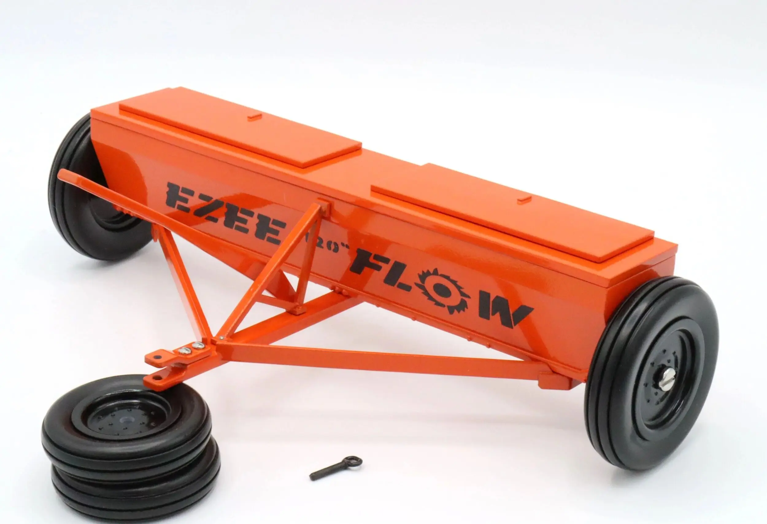 An orange EZEE FLOW agricultural seed planter attachment with wheels.