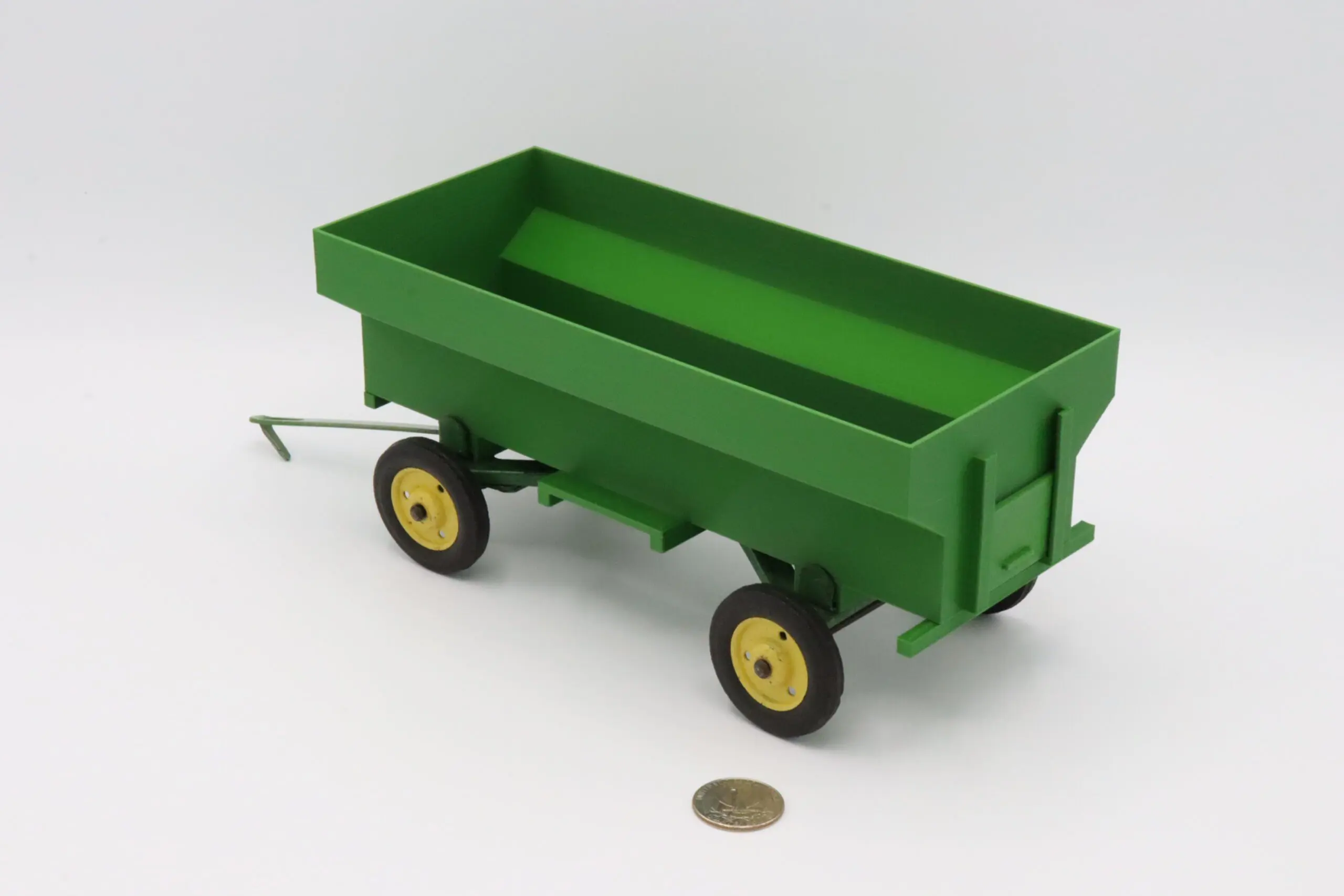 A small green toy wagon with yellow-rimmed wheels.