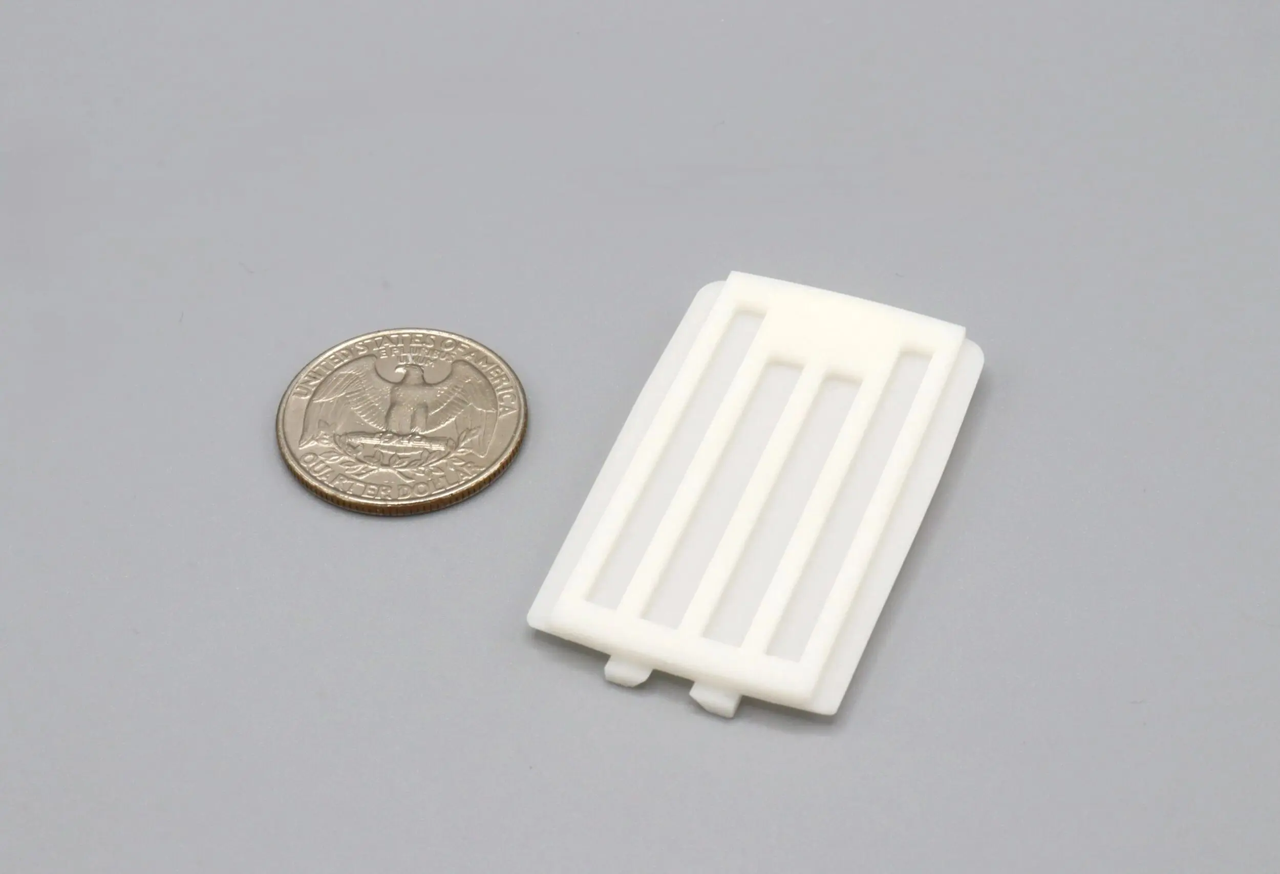Small white rectangular plastic object beside a coin for scale.