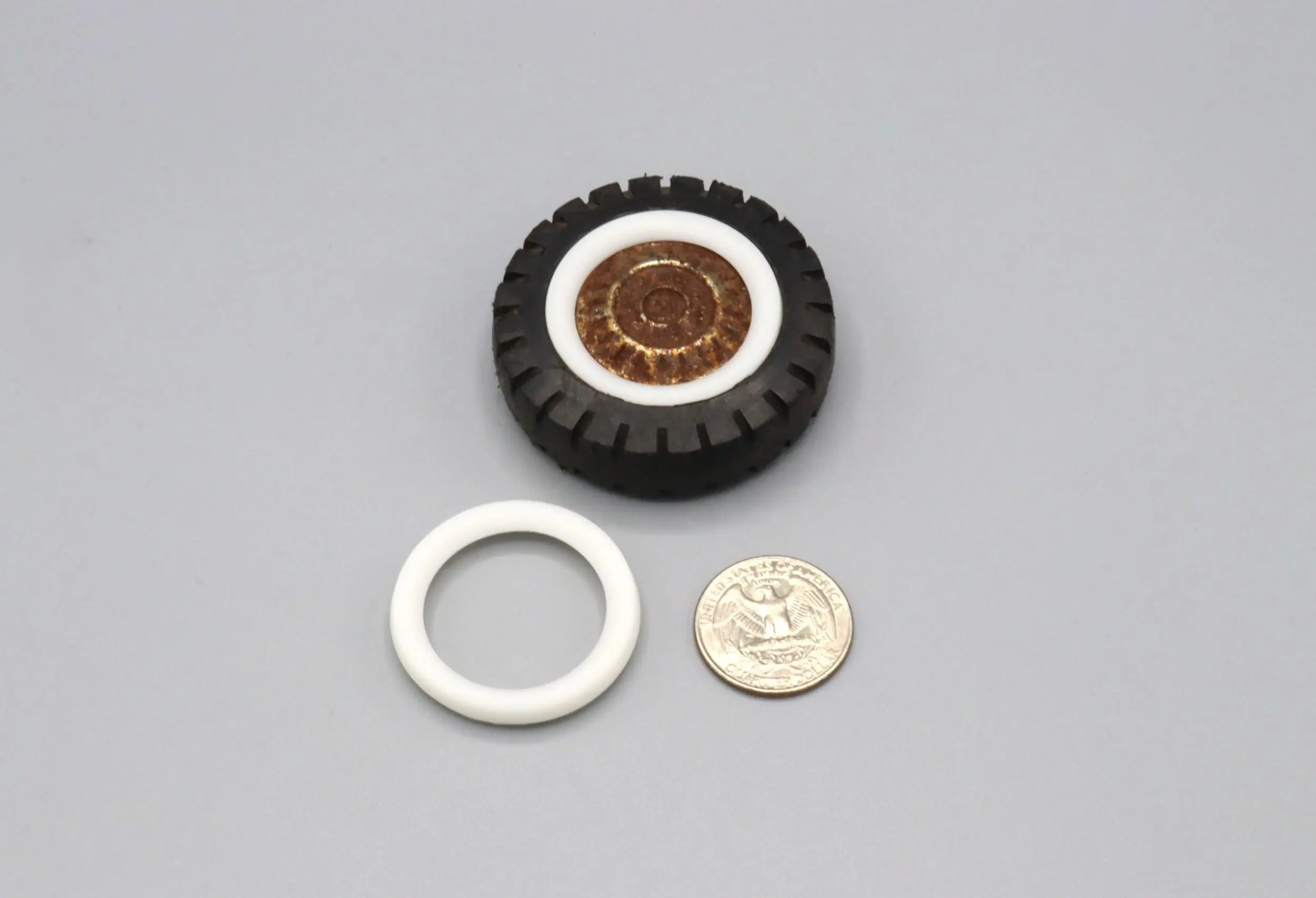 A disassembled circular device with a coin for scale.
