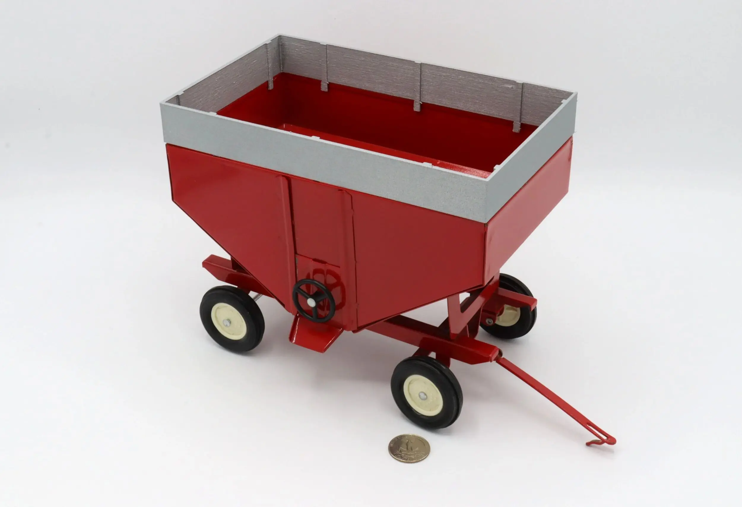 A small red wagon with a gray top and four wheels.
