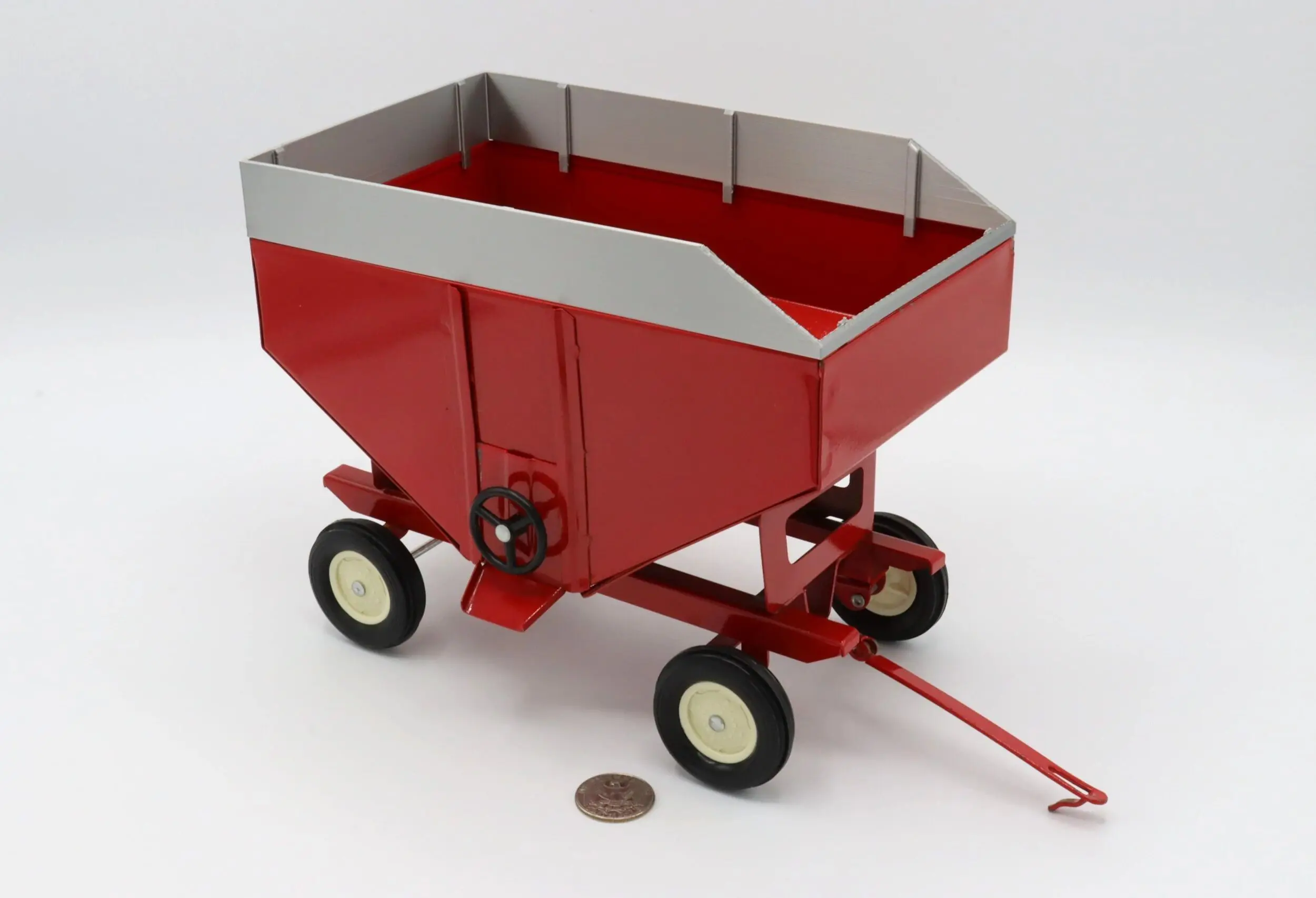 A red miniature wagon toy with four wheels and a handle.