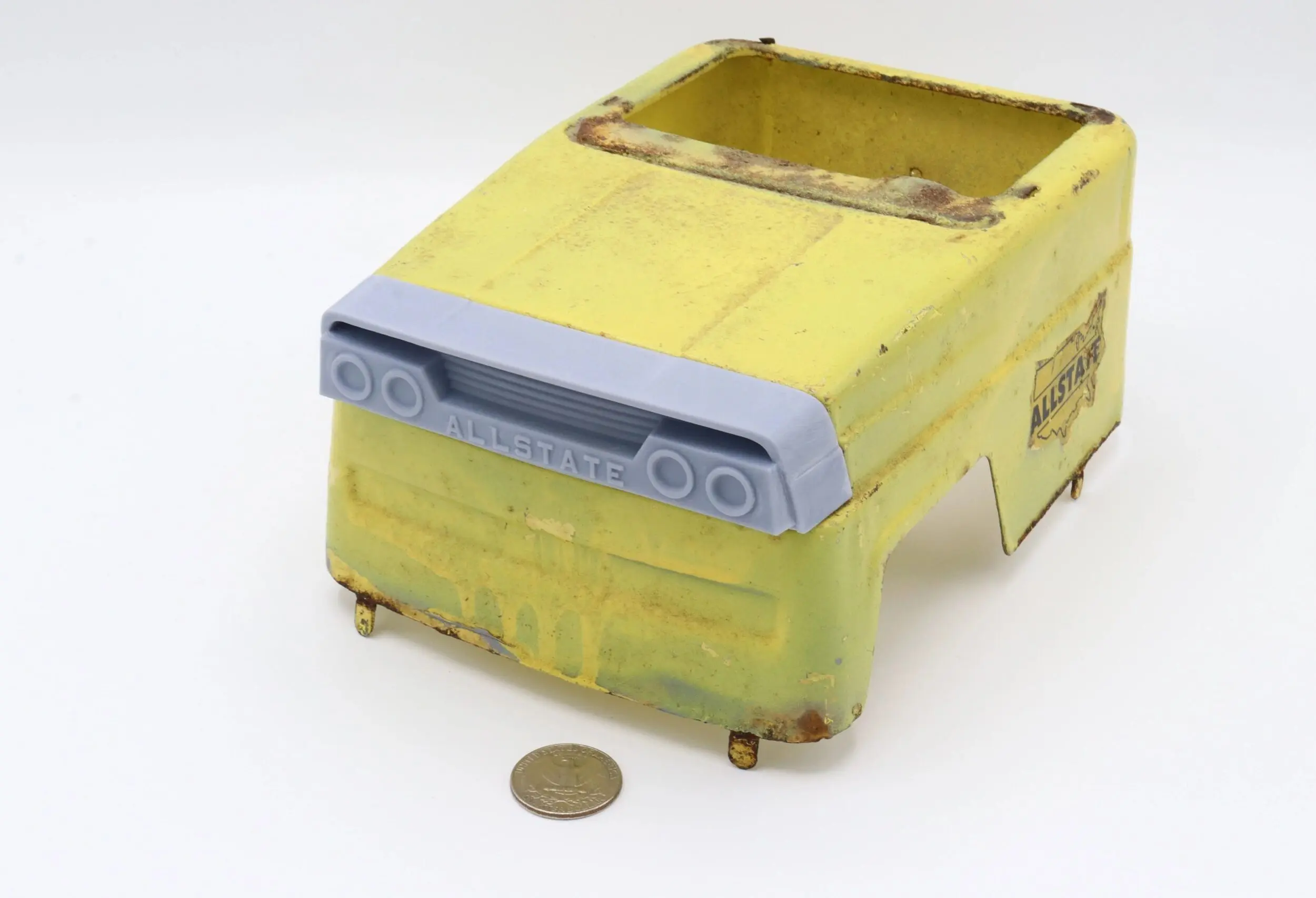 A rusty, yellow metal box with an old control panel and a coin for scale.