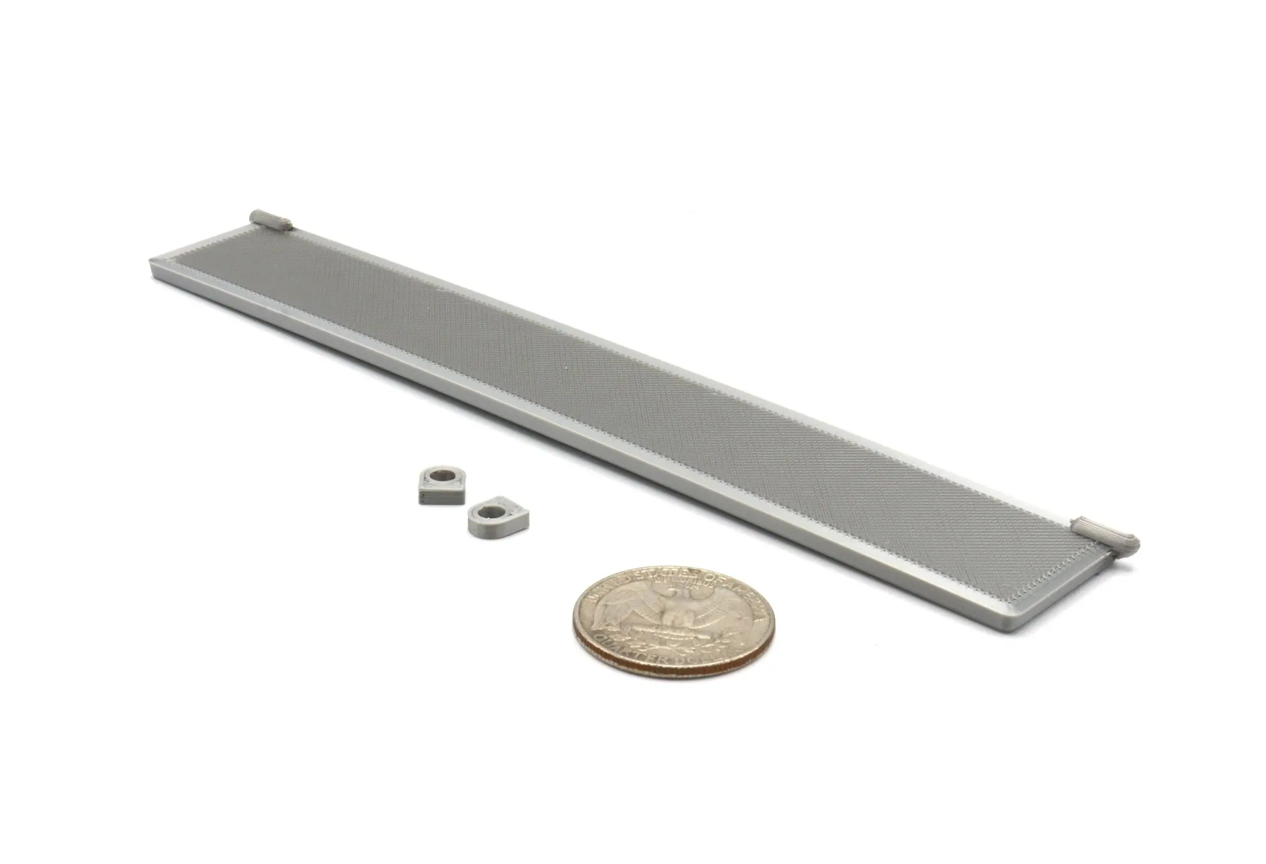 A gray metal bar with two small round magnets and a quarter for scale.