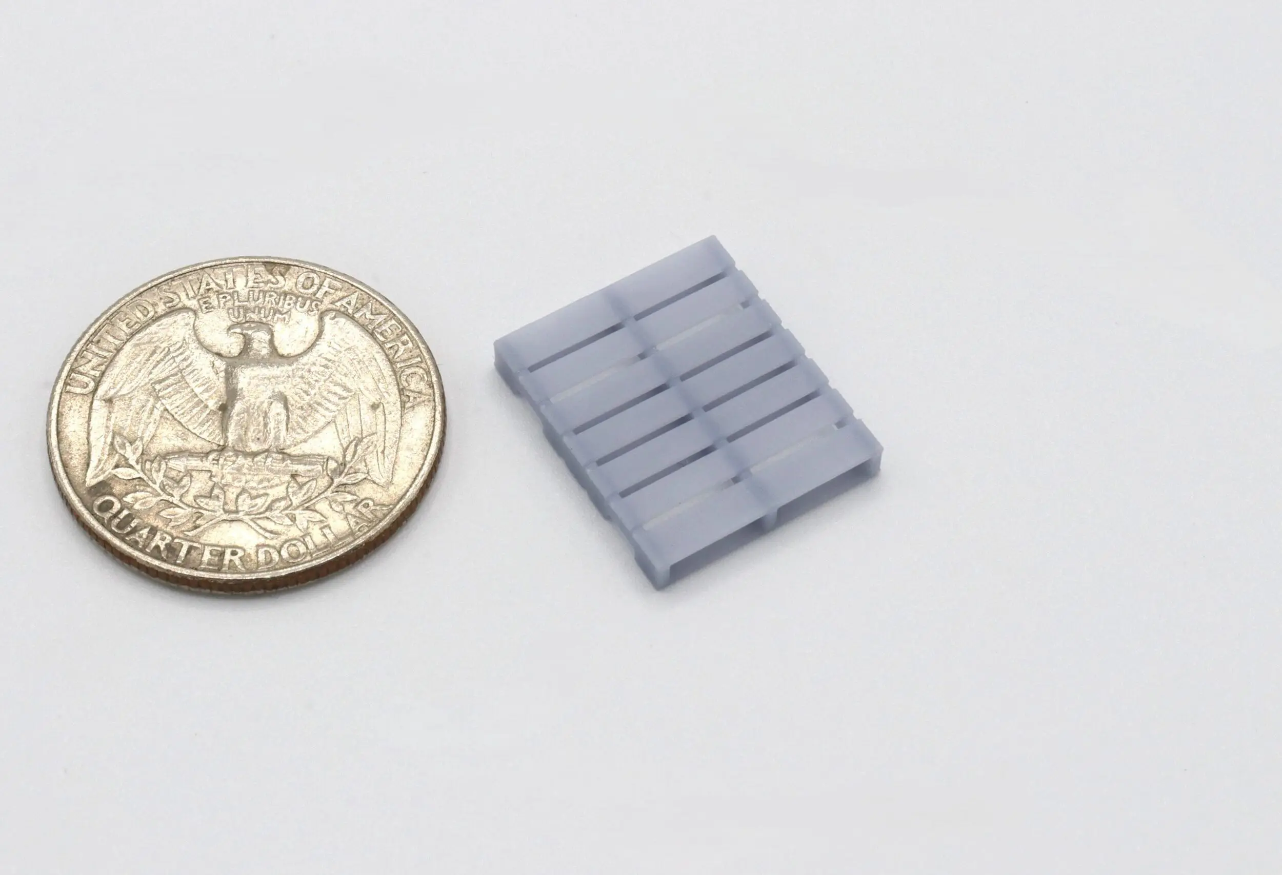 Small gray plastic component next to a coin for scale.