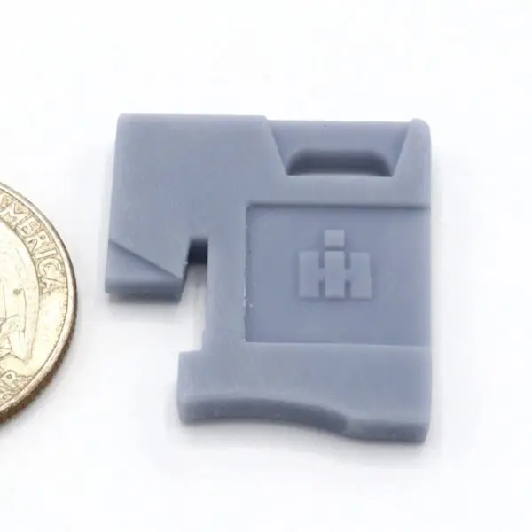 Small gray plastic piece with a logo next to a coin for scale.