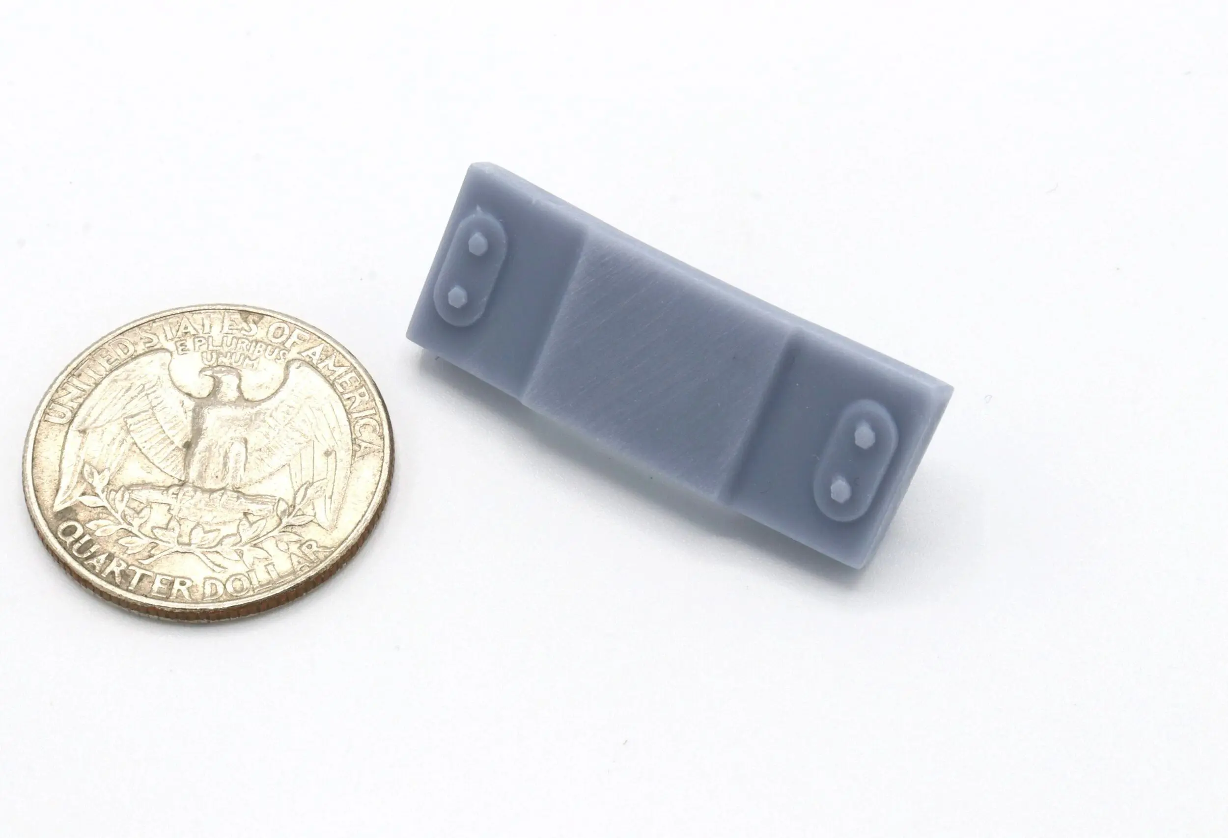Small gray electronic device next to a quarter for size.