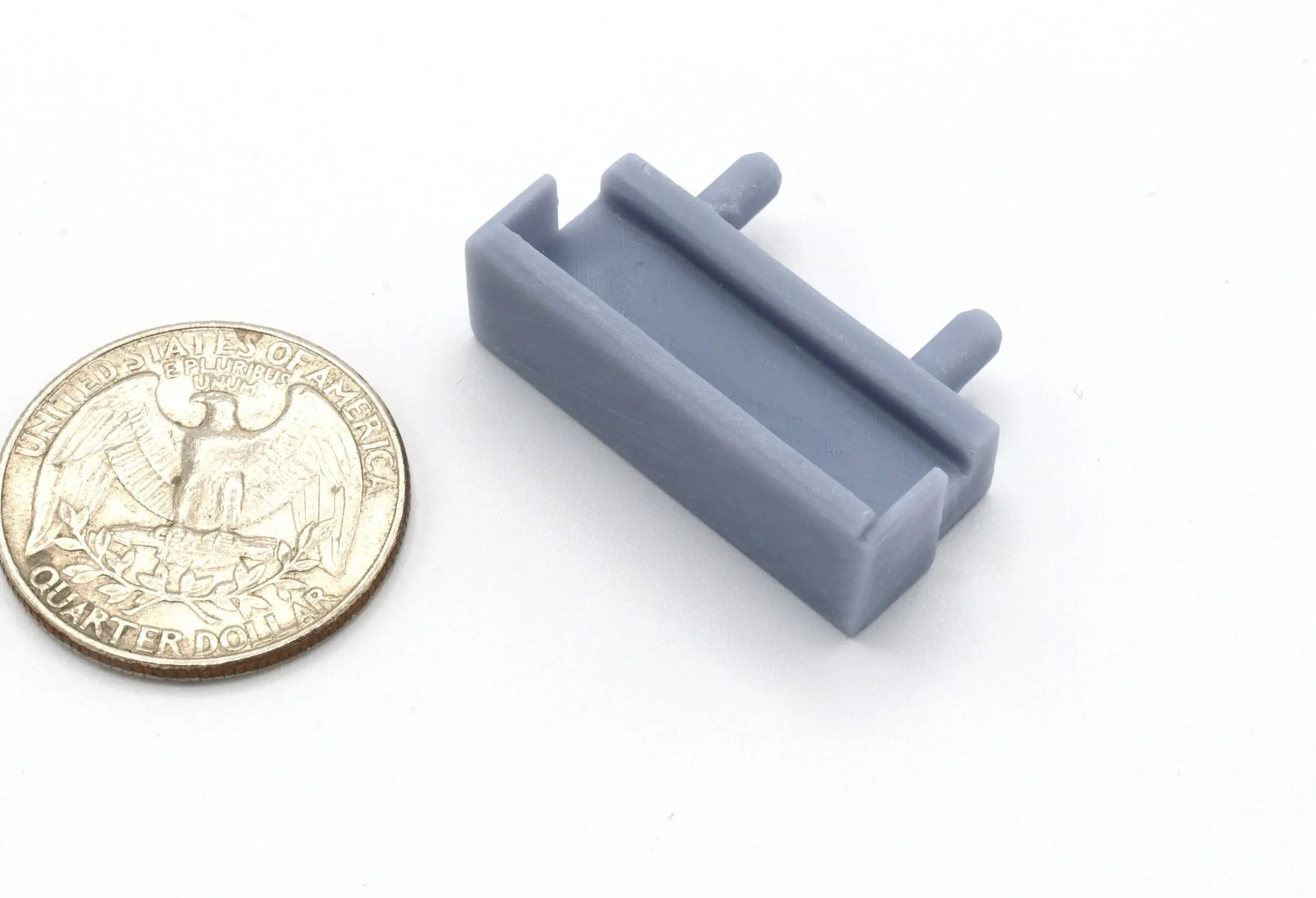 Small gray plastic LEGO part next to a quarter coin for scale.
