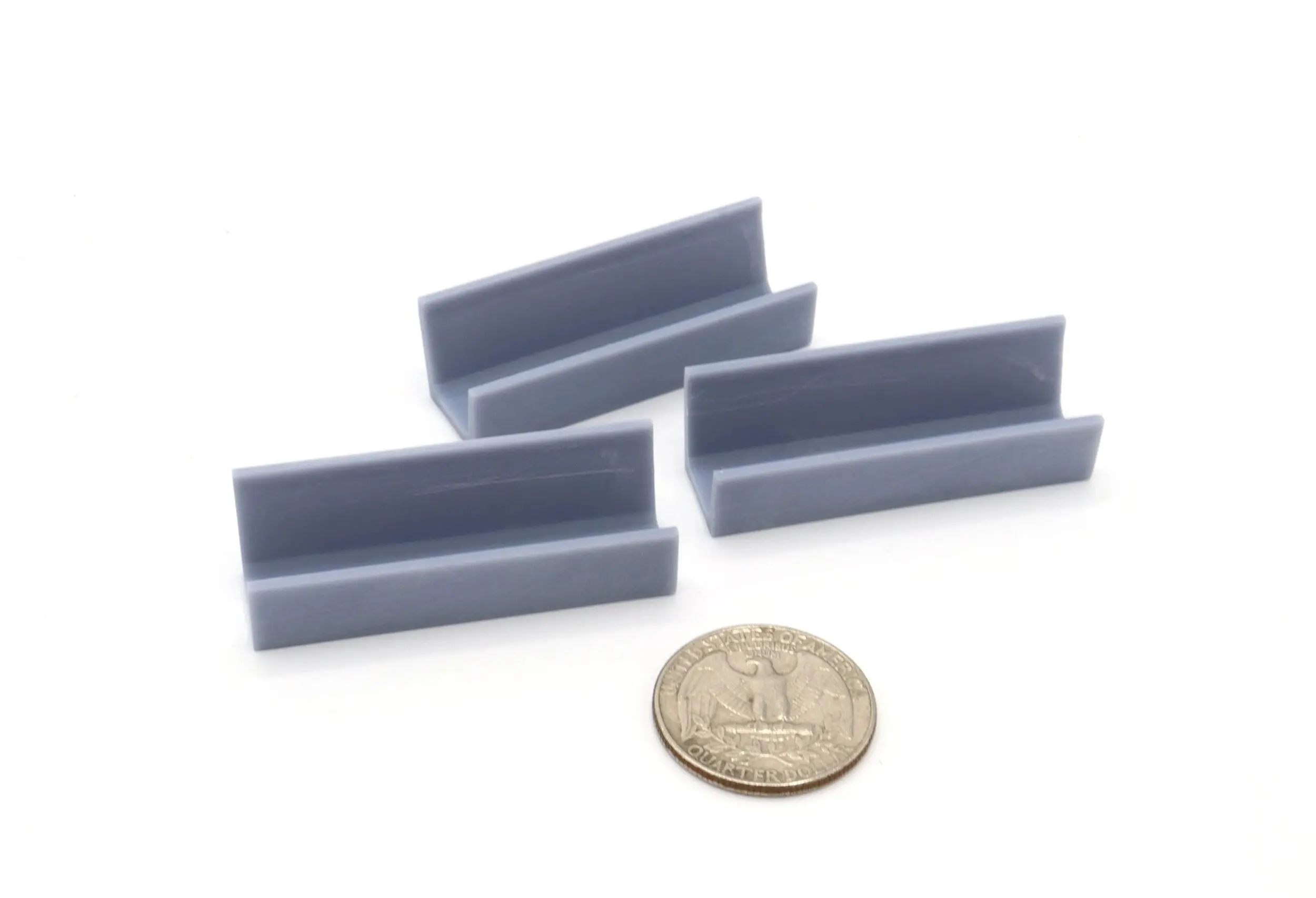 Three gray plastic clips next to a coin for size reference.