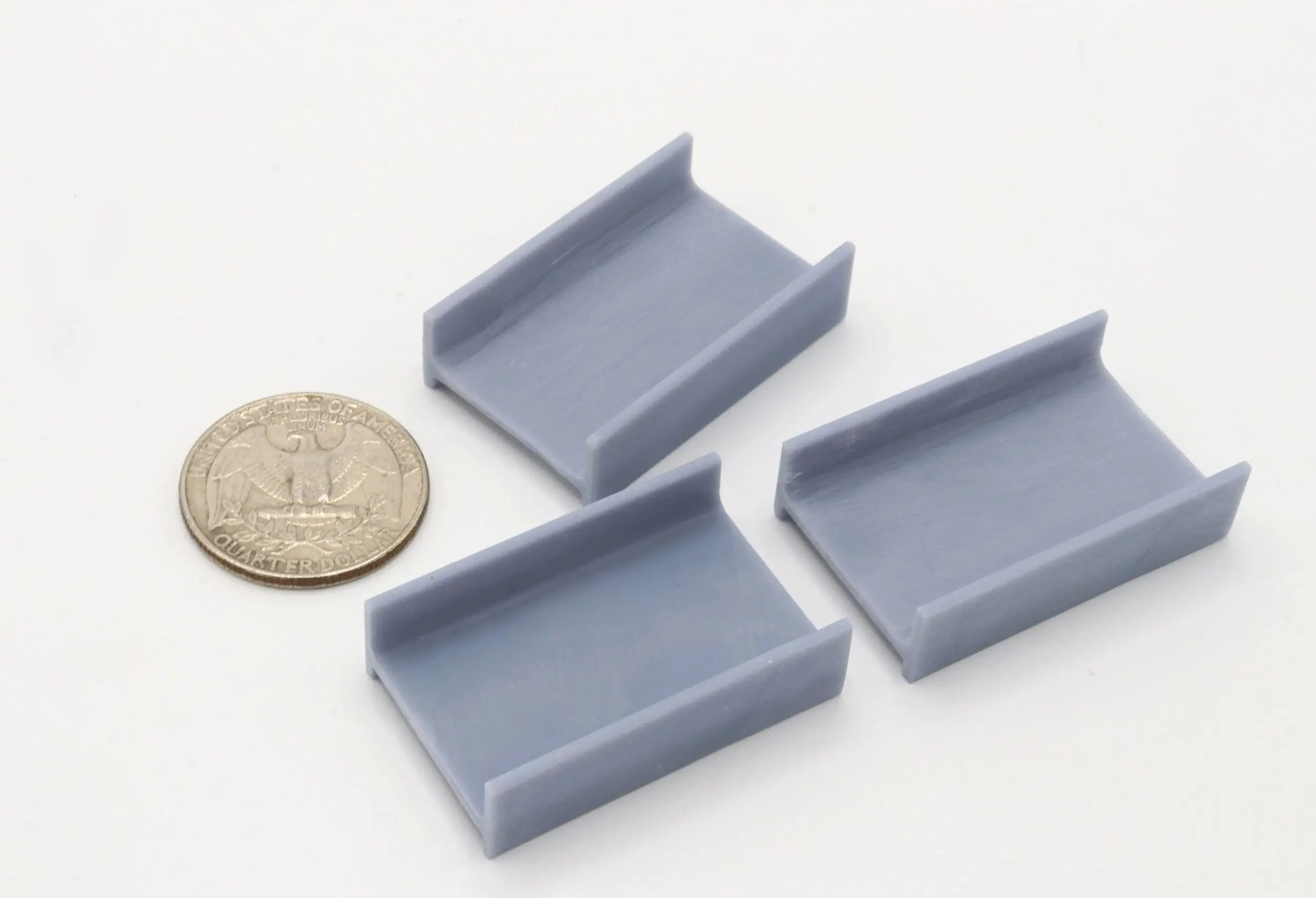 Small gray 3D-printed rectangular objects beside a coin for scale.