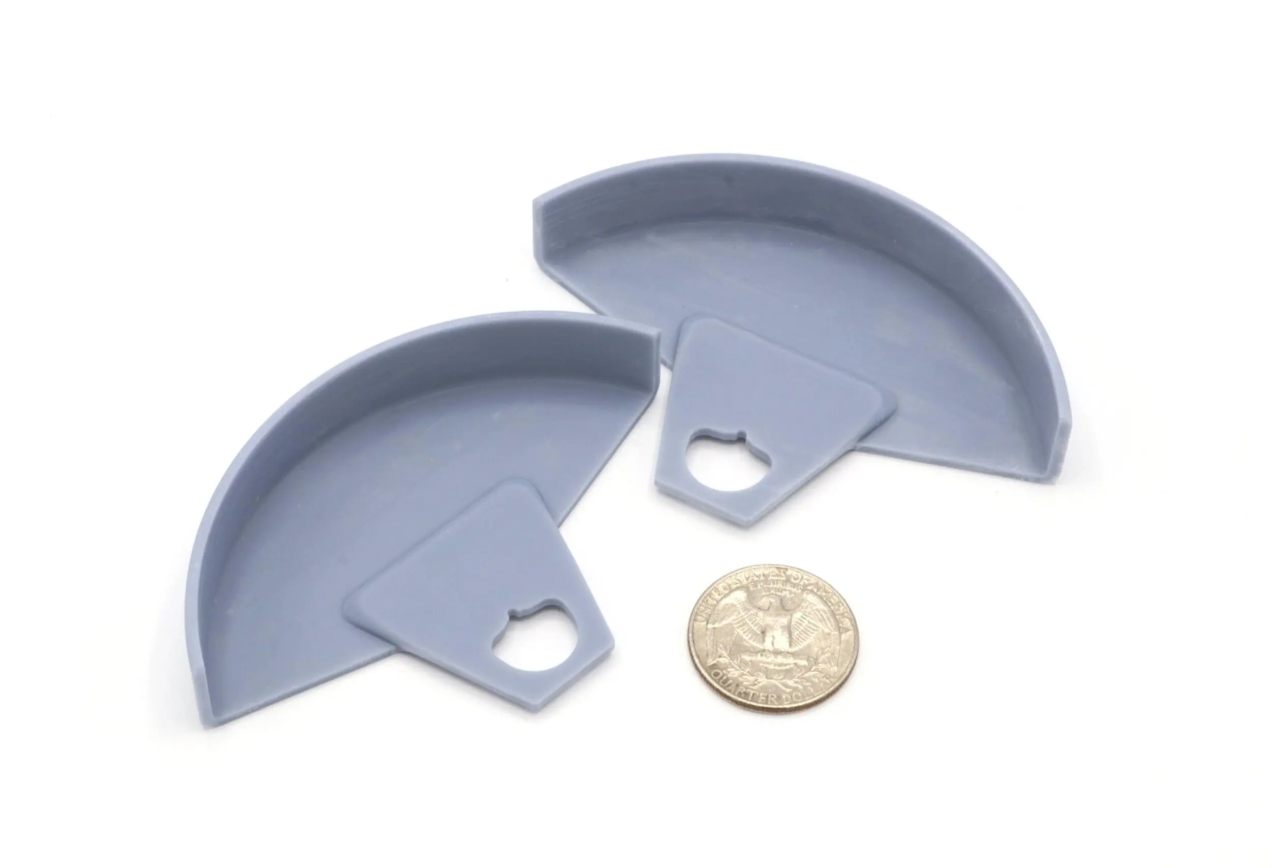 Two gray plastic corner protectors next to a quarter for scale.