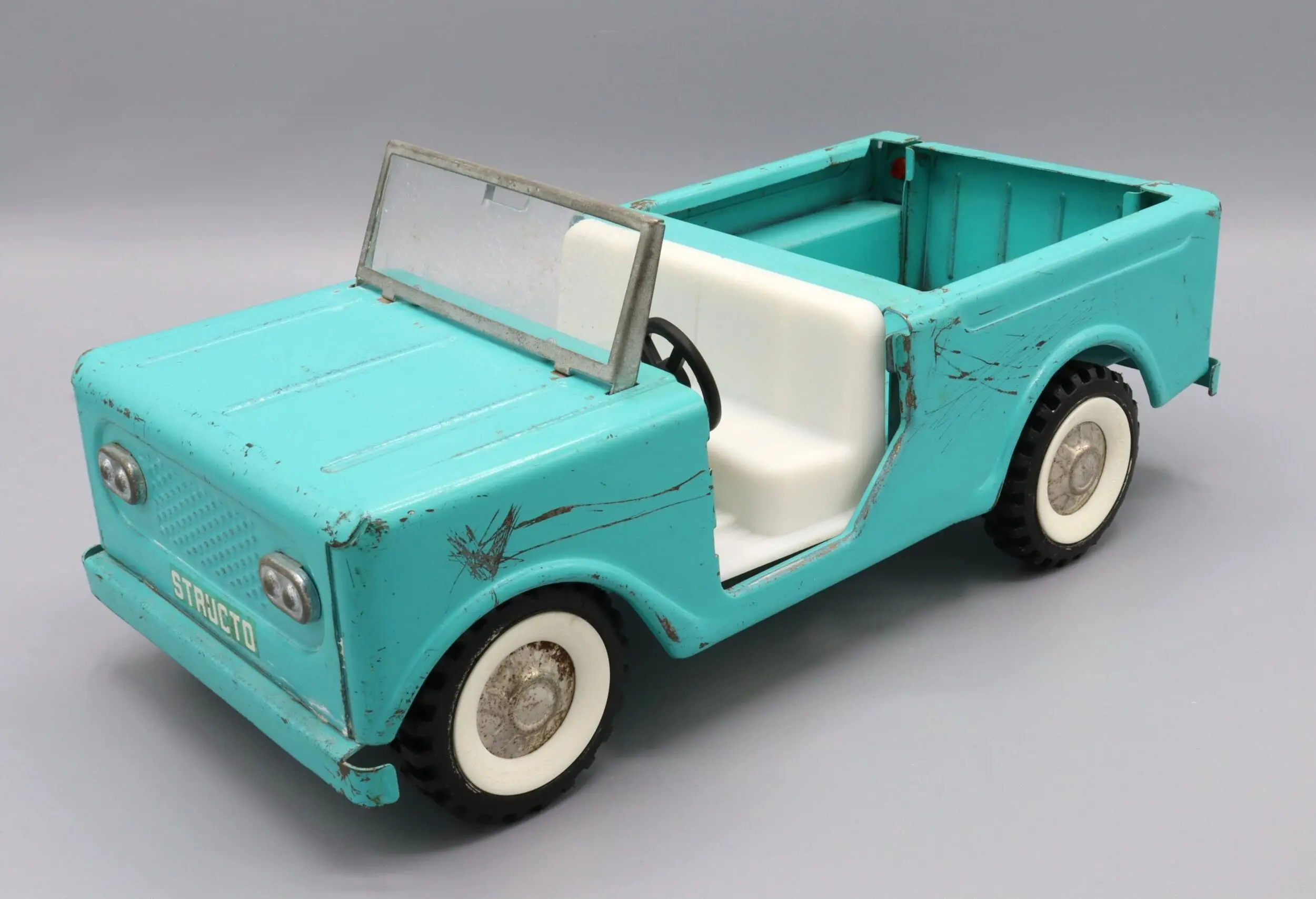Vintage turquoise toy car with white seats and windshield.