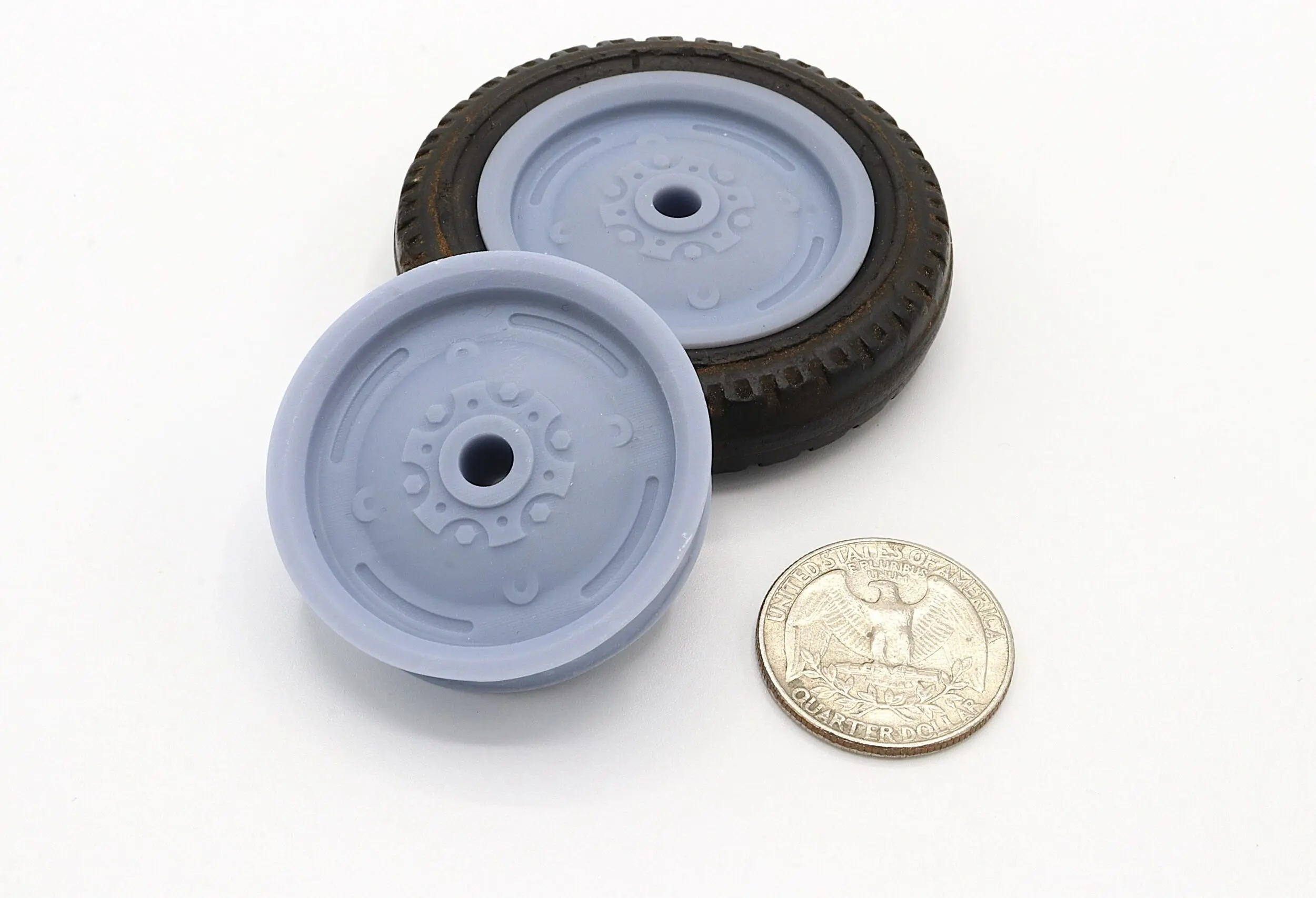Two small model wheels next to a quarter for size comparison.