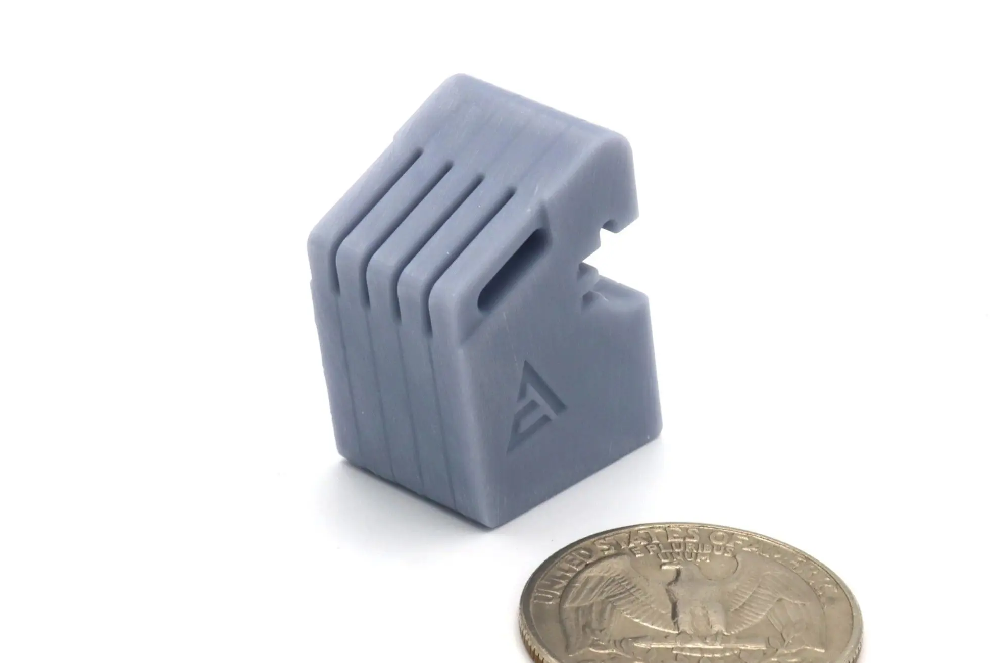 Small gray plastic object with a notch and ridges, next to a coin for scale.