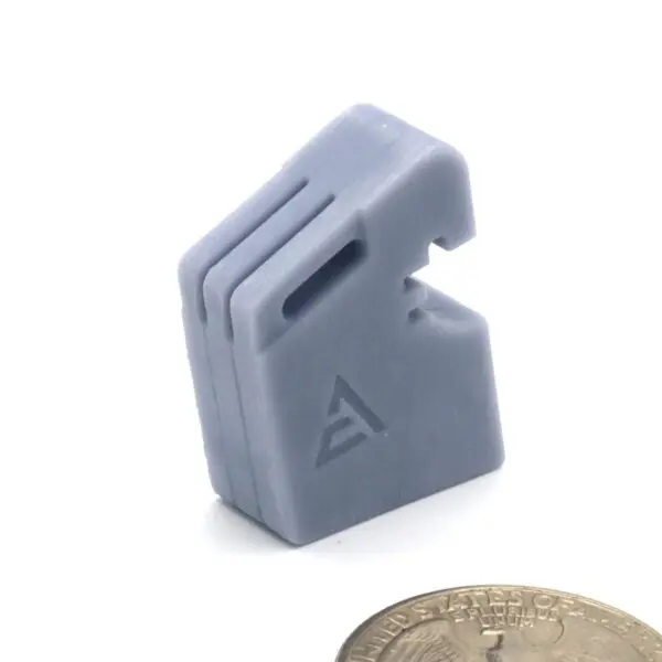 Small gray plastic component with a triangular logo and slots.
