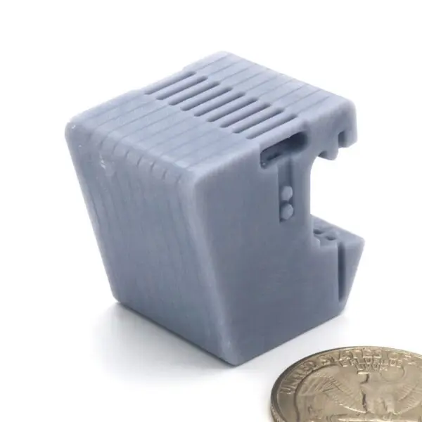 Small gray electronic component next to a coin for scale.