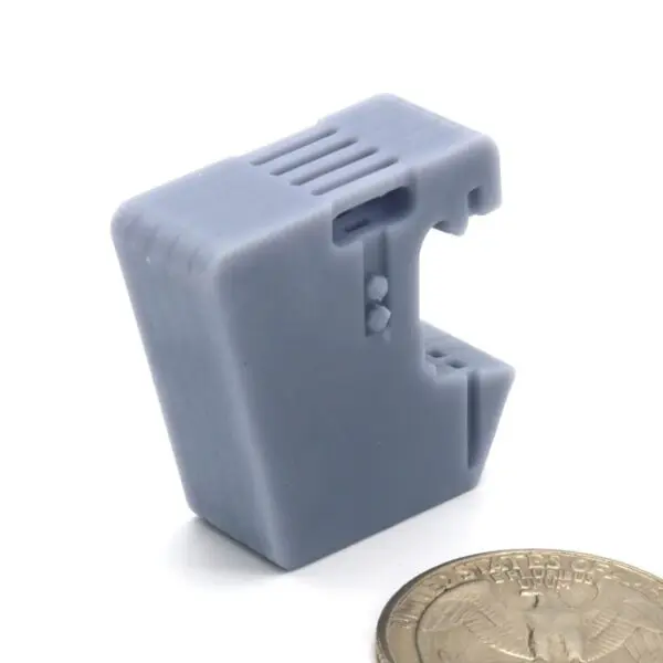 Small gray plastic device with a clip, next to a coin for scale.