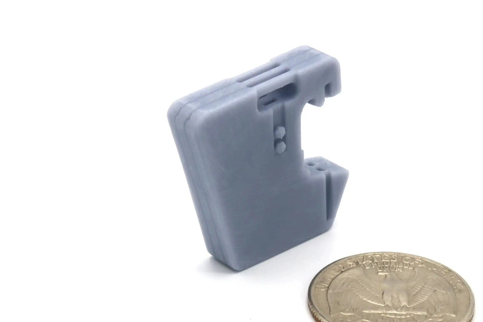 Small gray plastic device with a clip, next to a coin for scale.