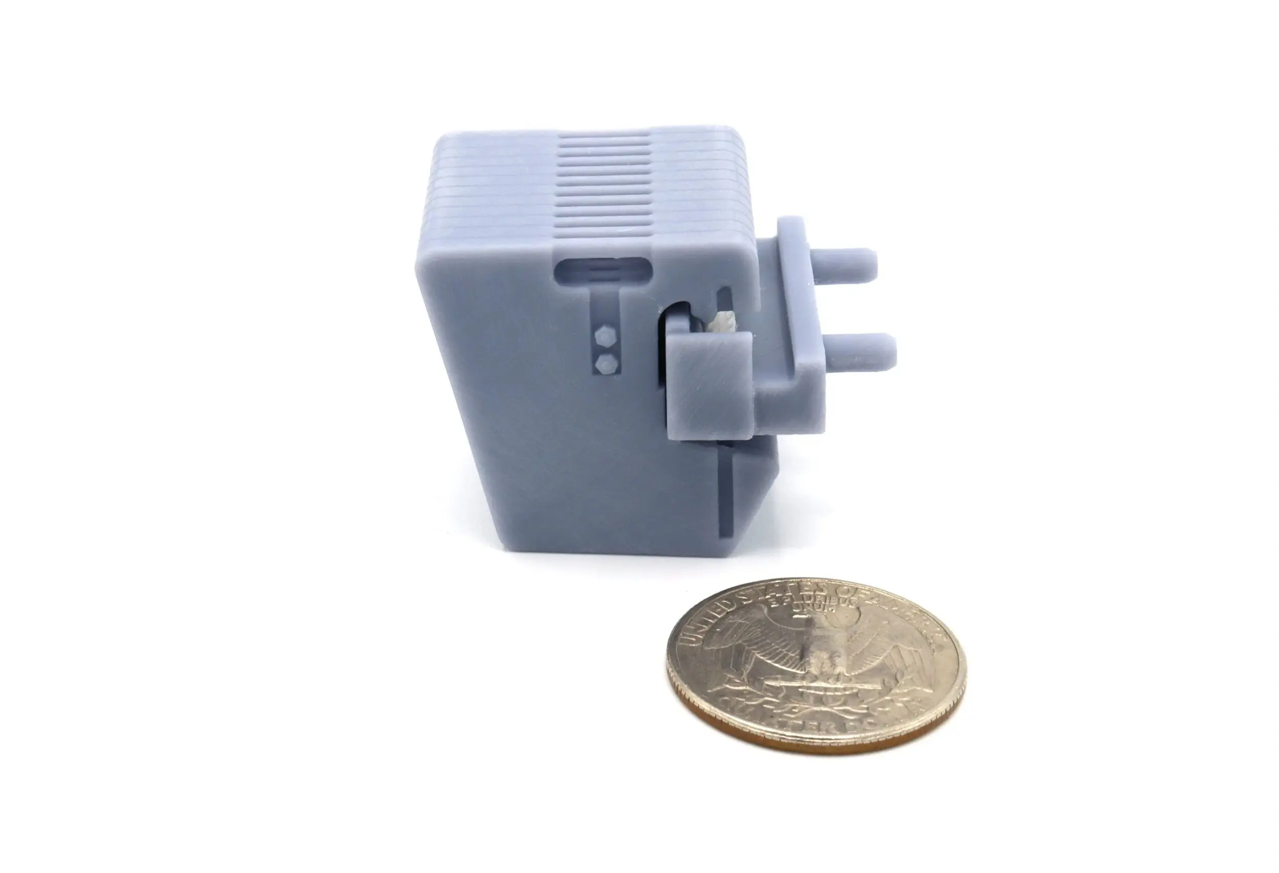 Small gray plastic mechanical part next to a coin for scale.