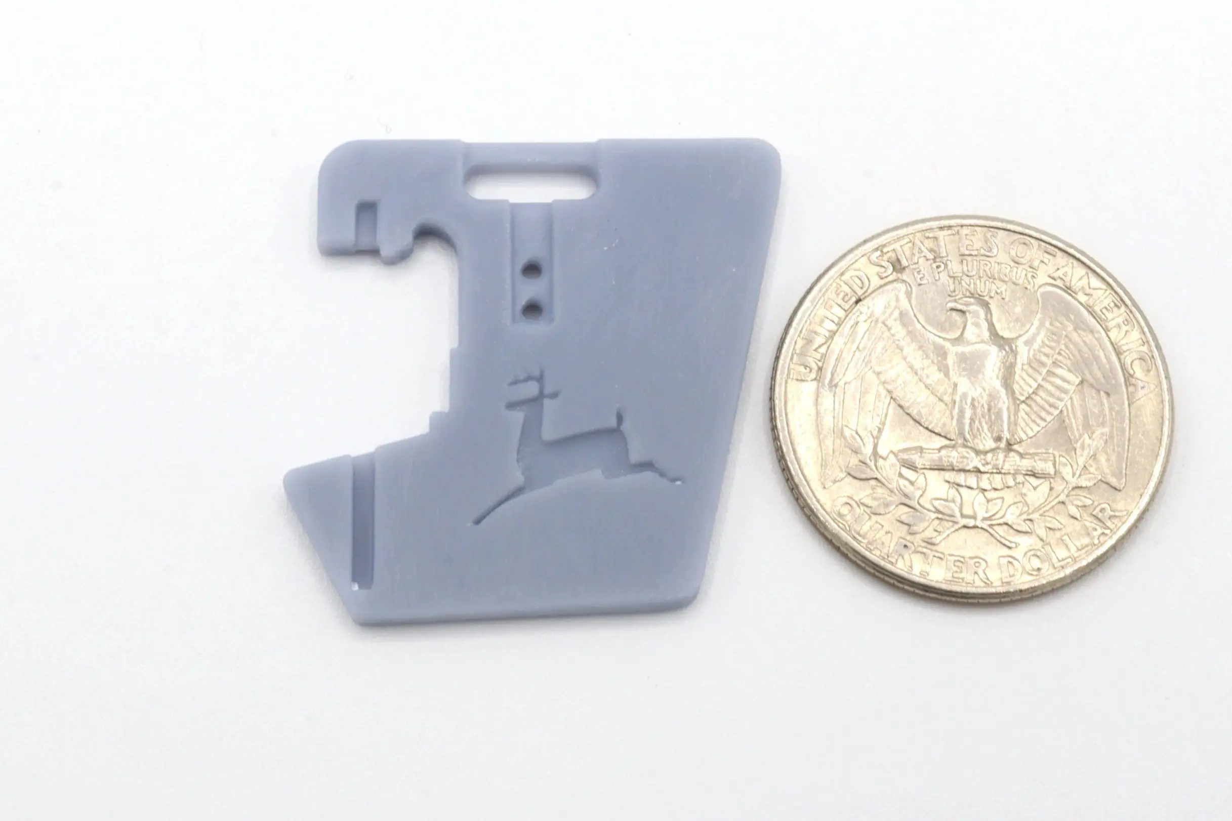 Small gray plastic object next to a quarter for scale.