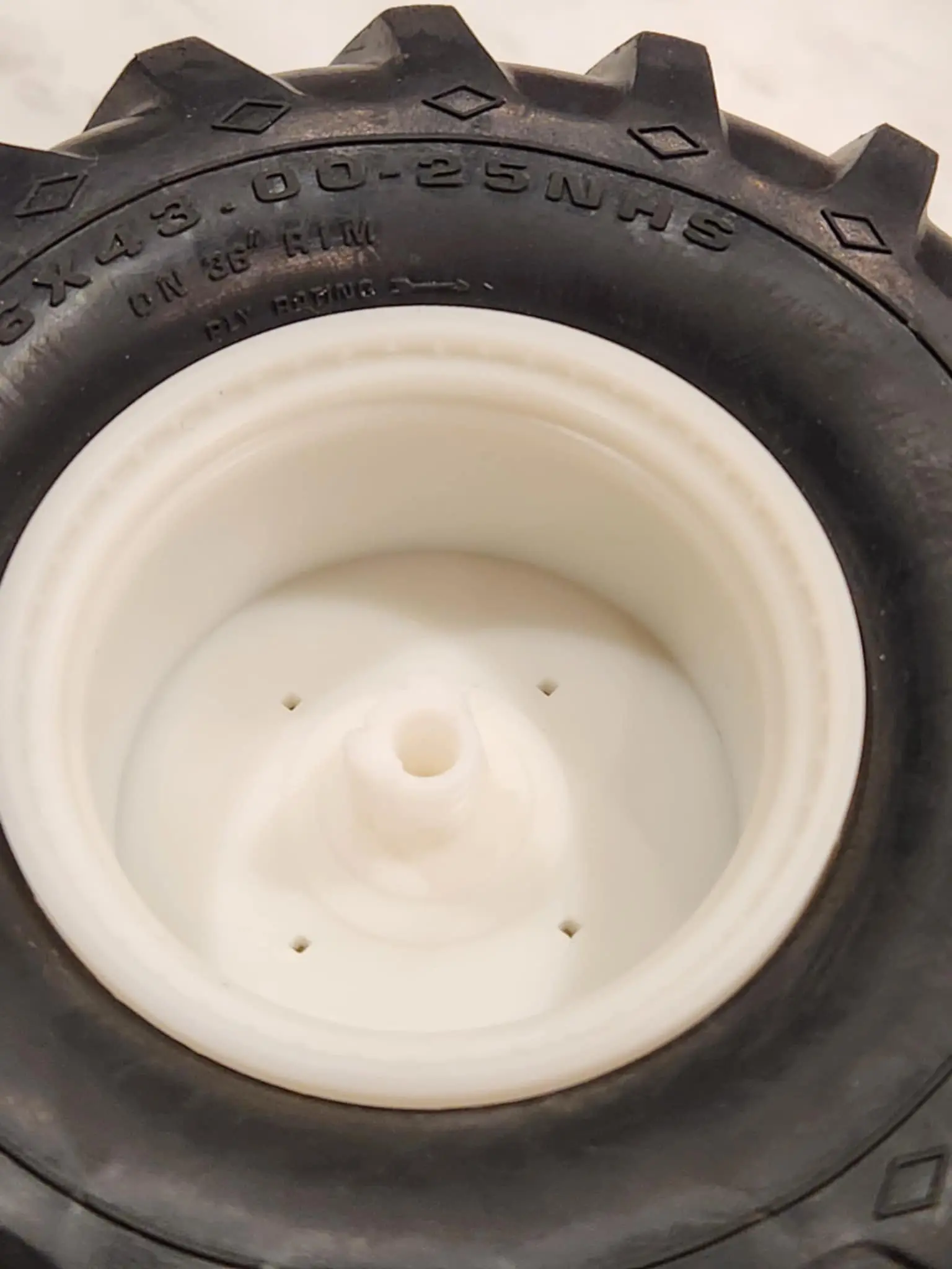 Close-up of a white plastic wheel hub and black tire.