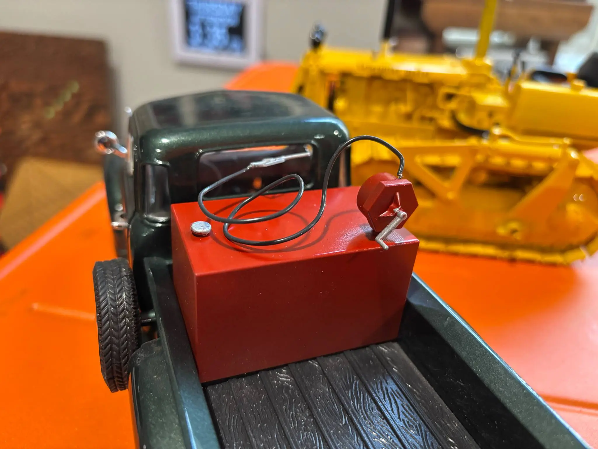 Close-up of a toy truck carrying a red container with coiled cables.