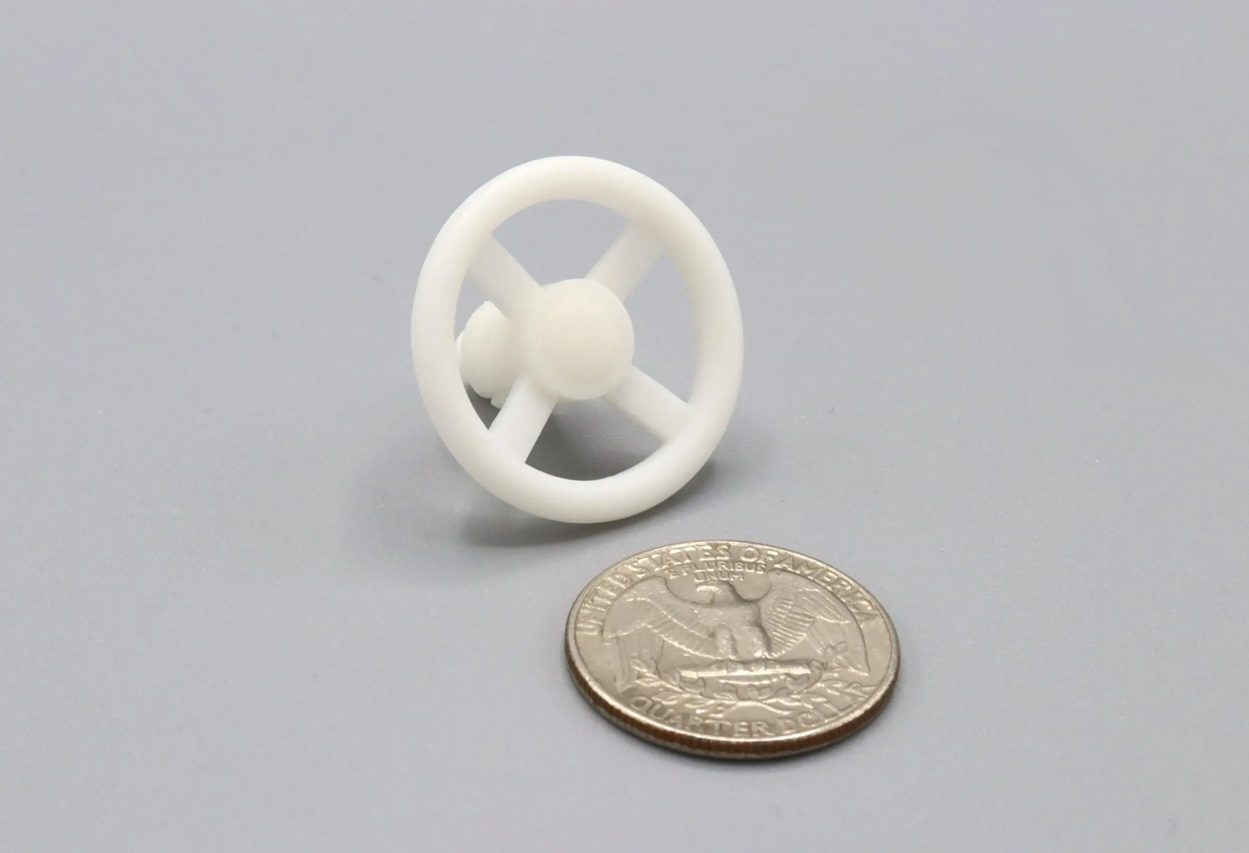 White plastic wheel beside a quarter coin.