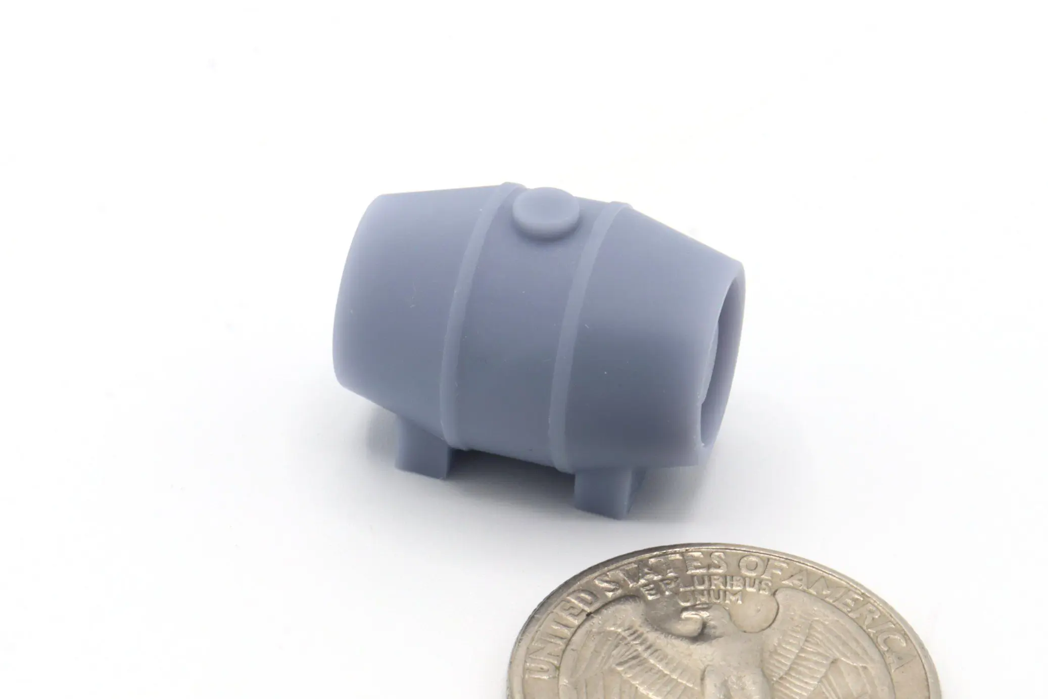 Gray miniature barrel beside a coin.