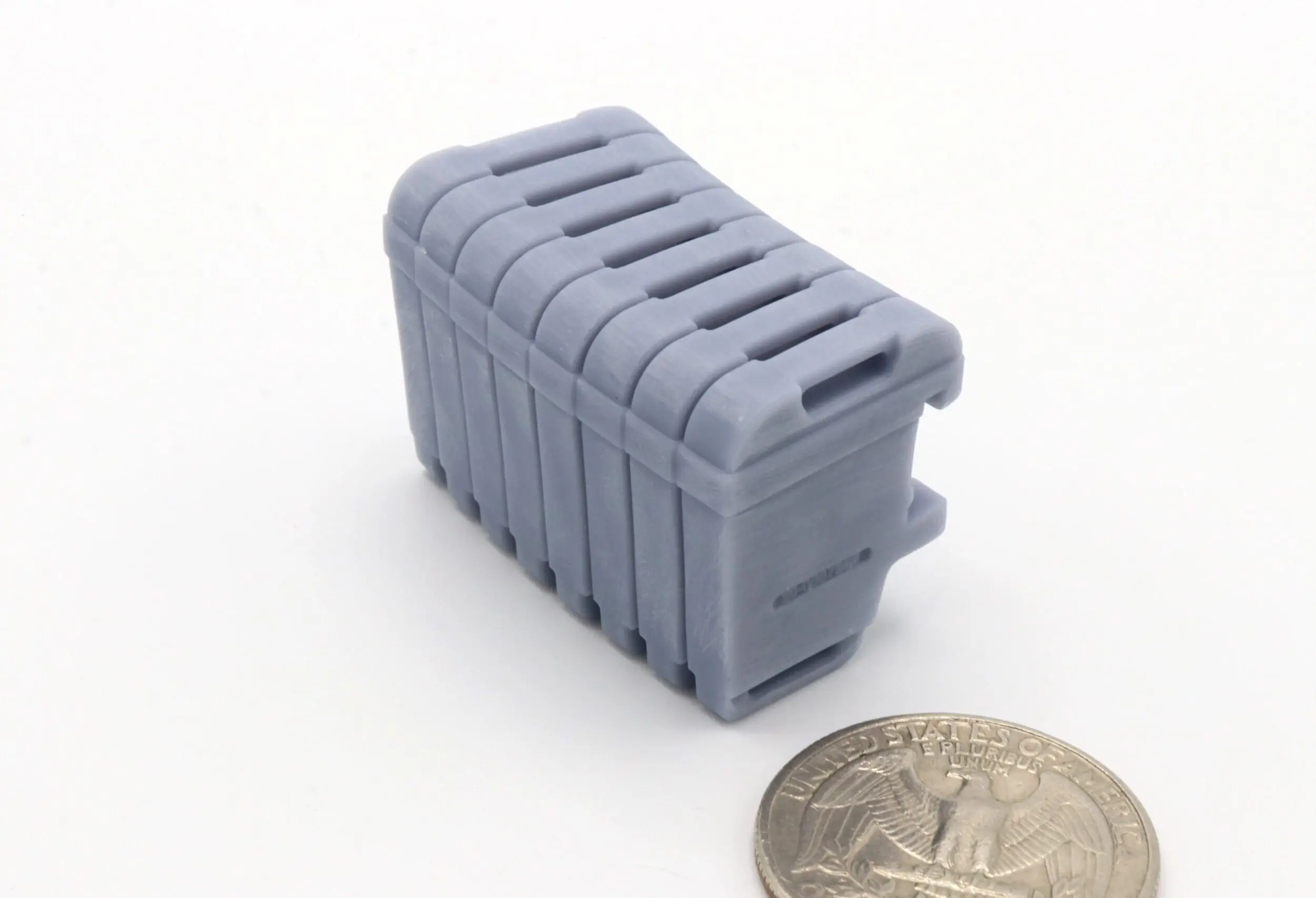 Gray plastic object next to a coin.