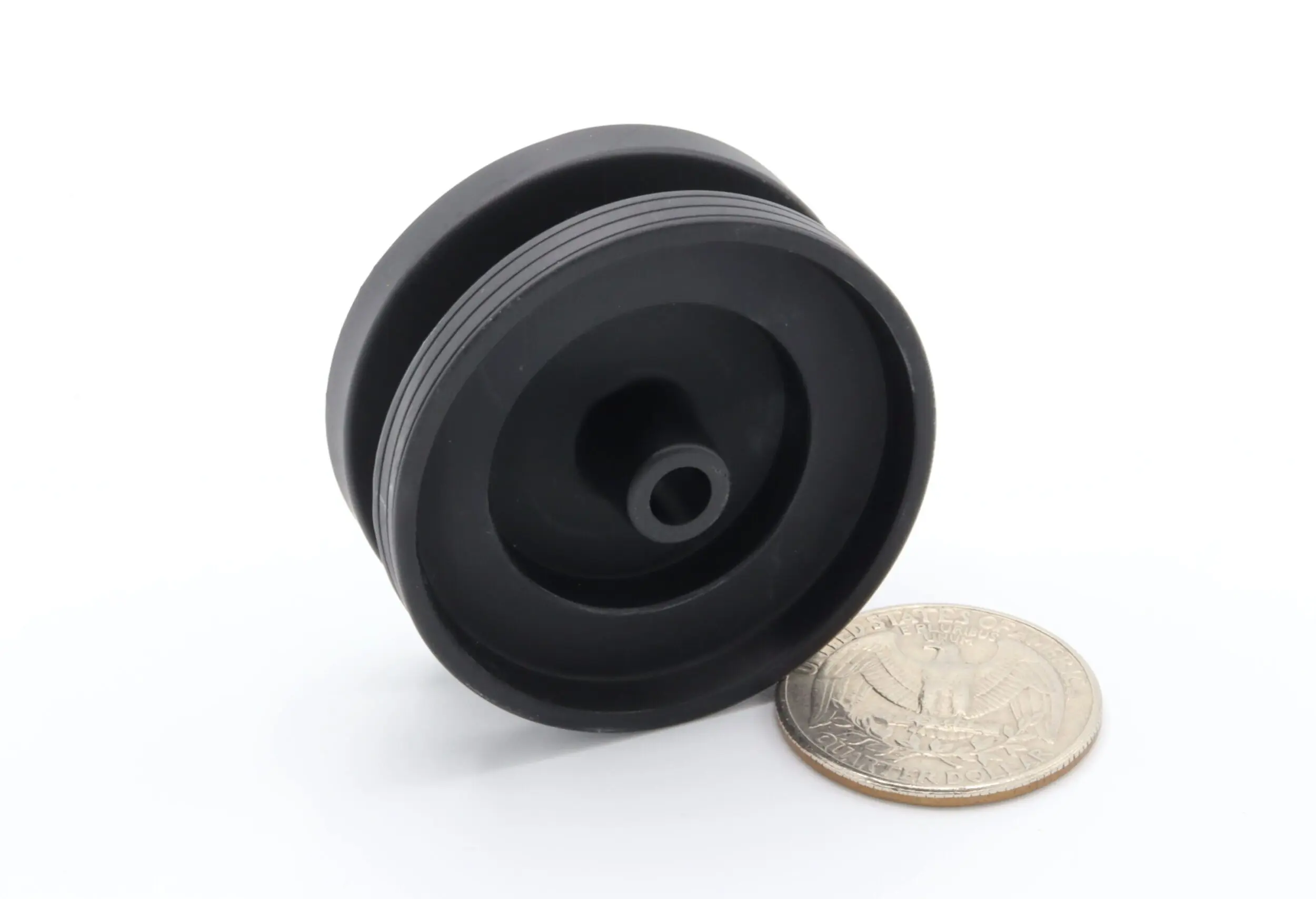 Black rubber pulley beside a coin.