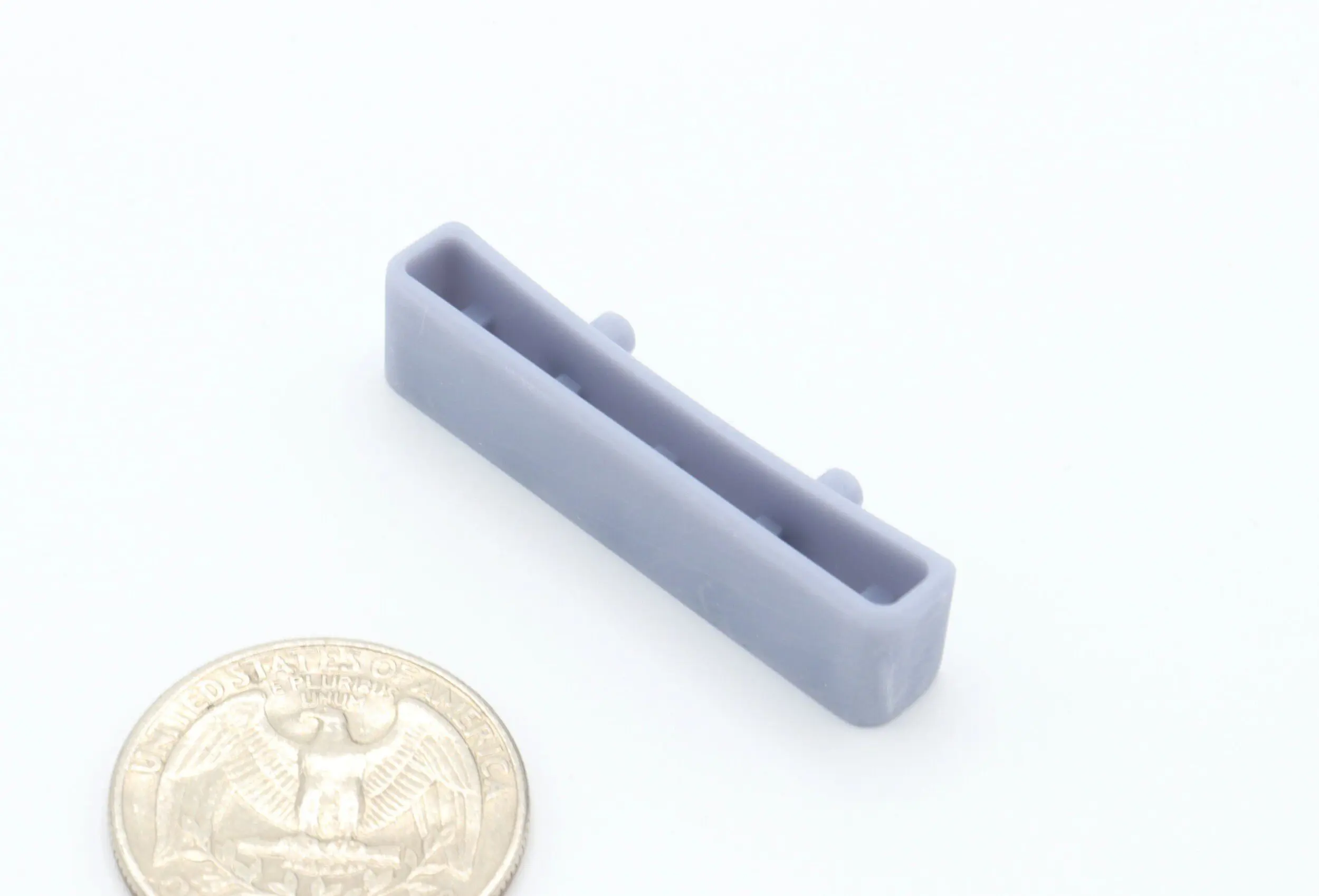 Gray plastic part beside a coin.