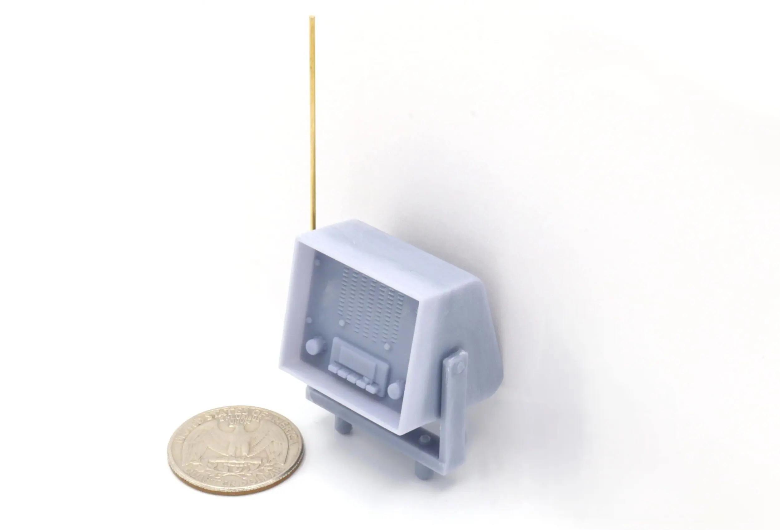 Miniature vintage TV with coin for scale.