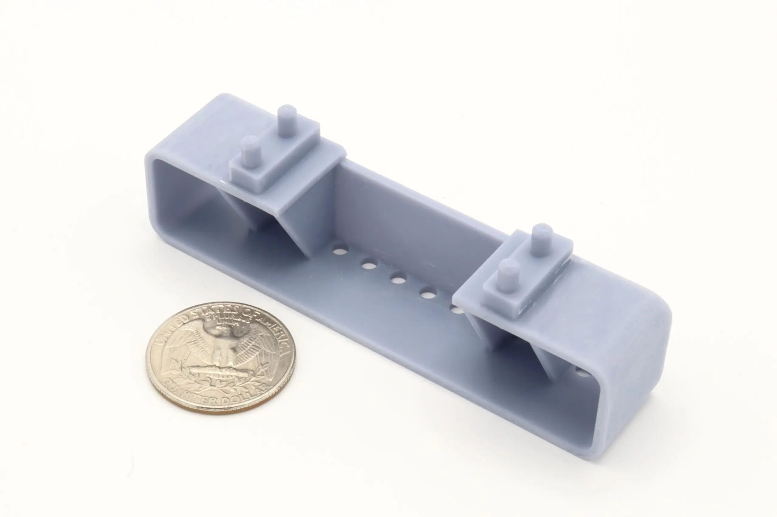 Gray plastic bracket beside a quarter coin.