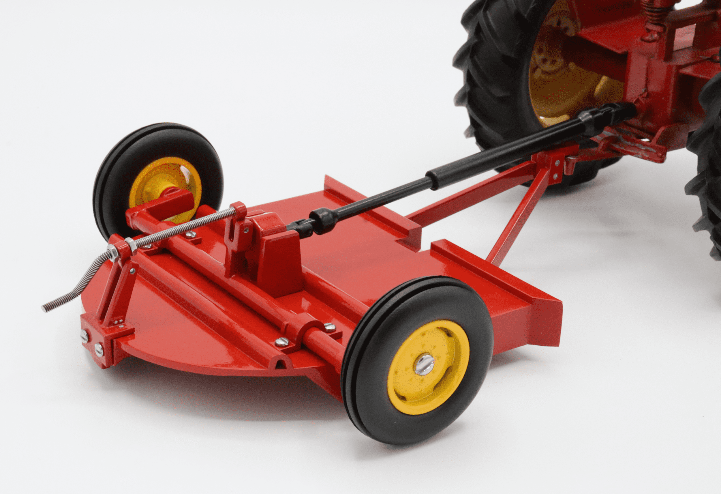 Red tractor with yellow-wheeled mower attachment.