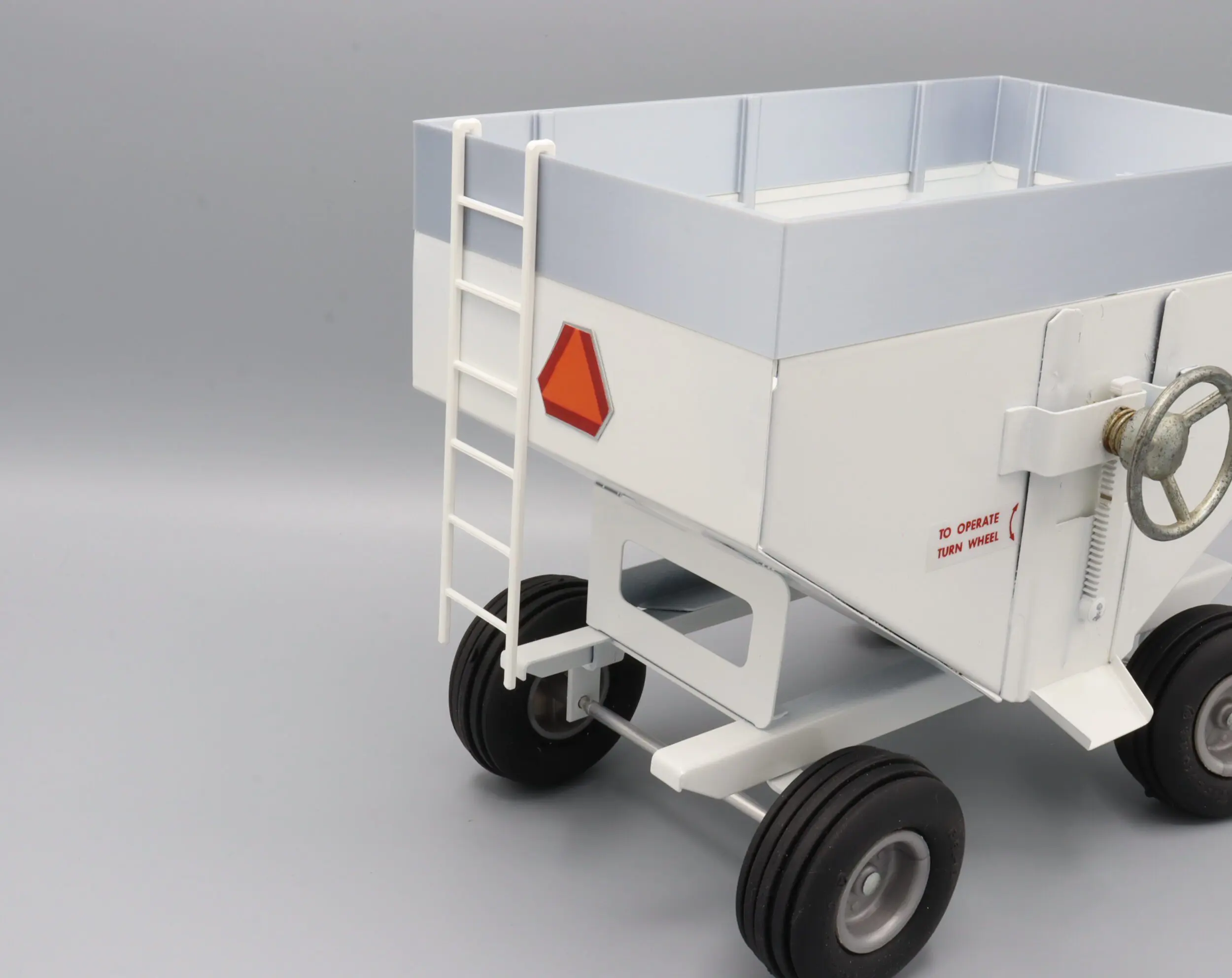 White agricultural trailer with ladder and wheels.