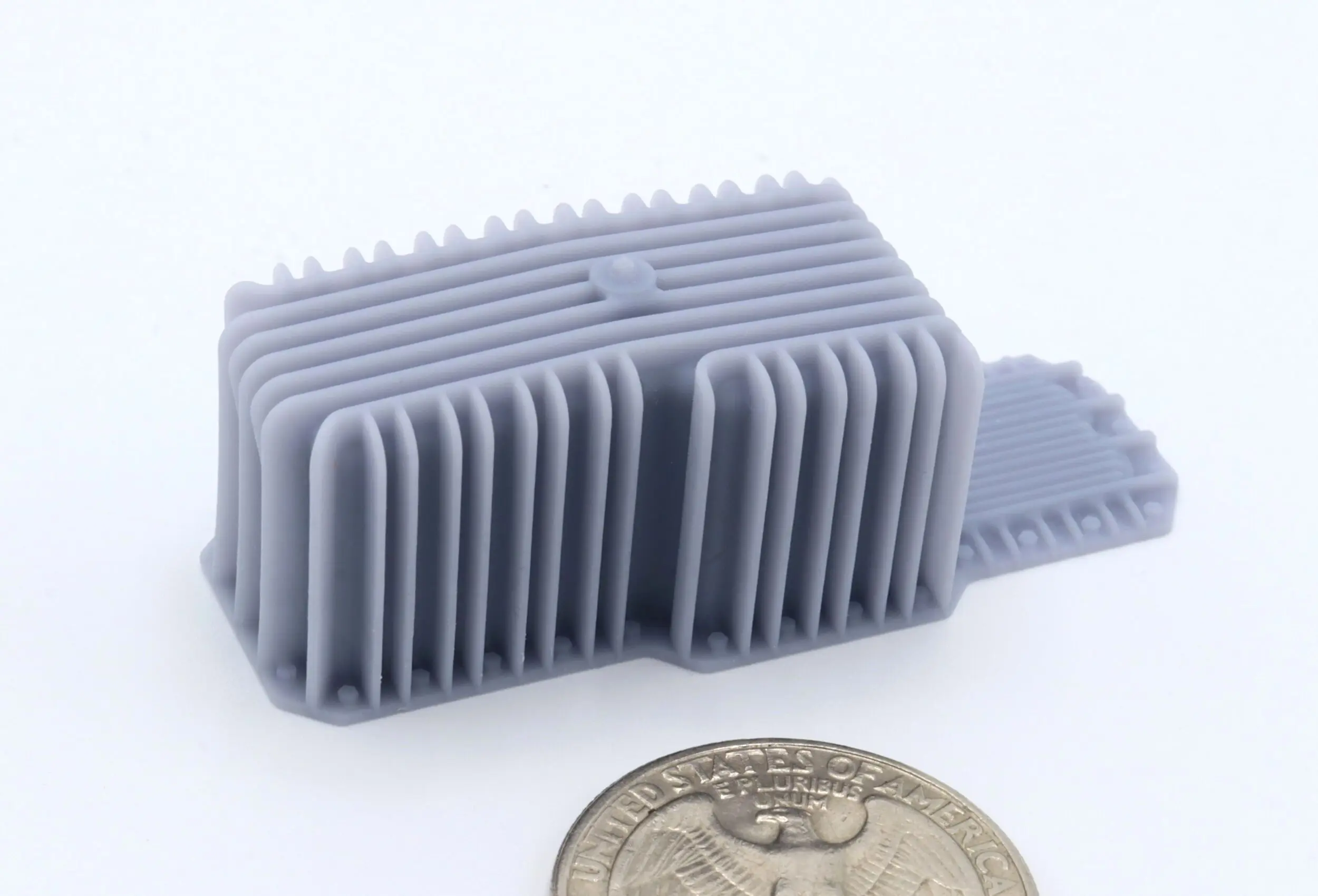 Gray 3D-printed object beside a coin.