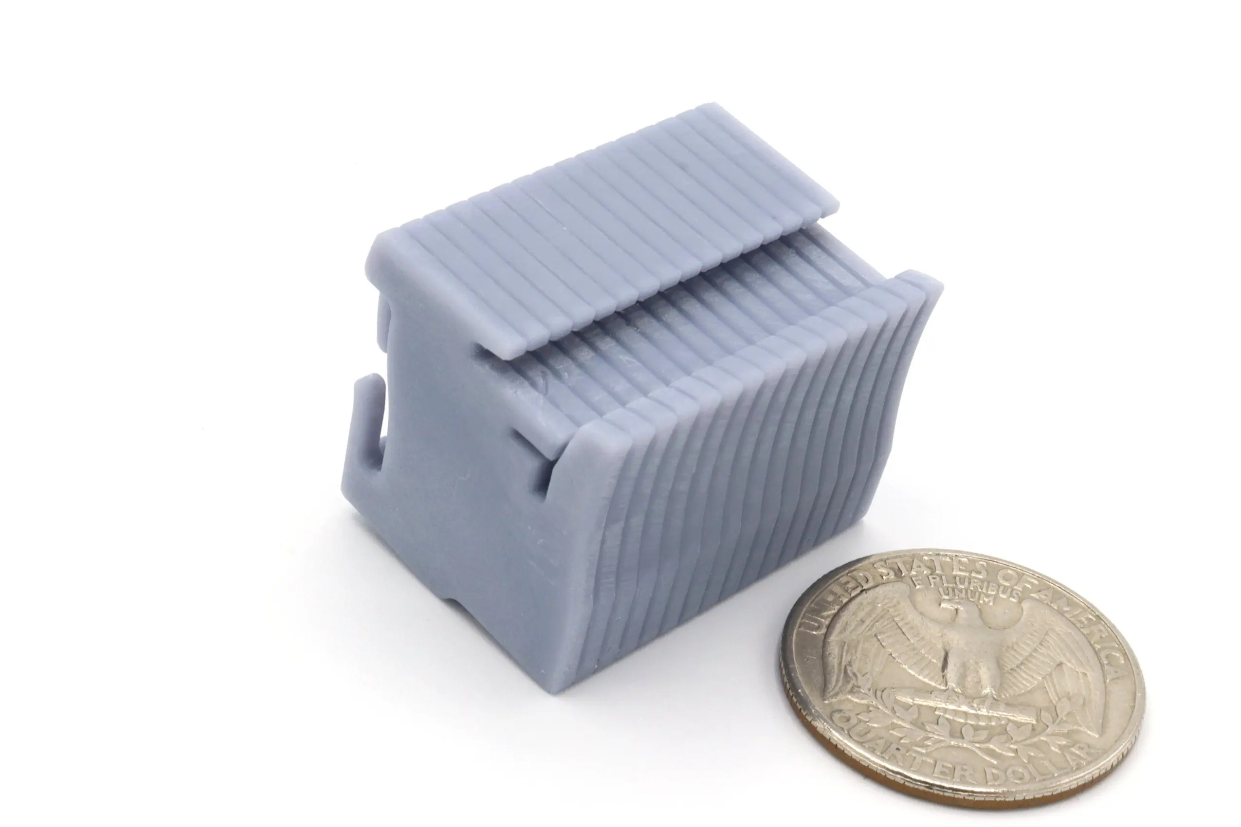 Gray plastic component beside a quarter coin.