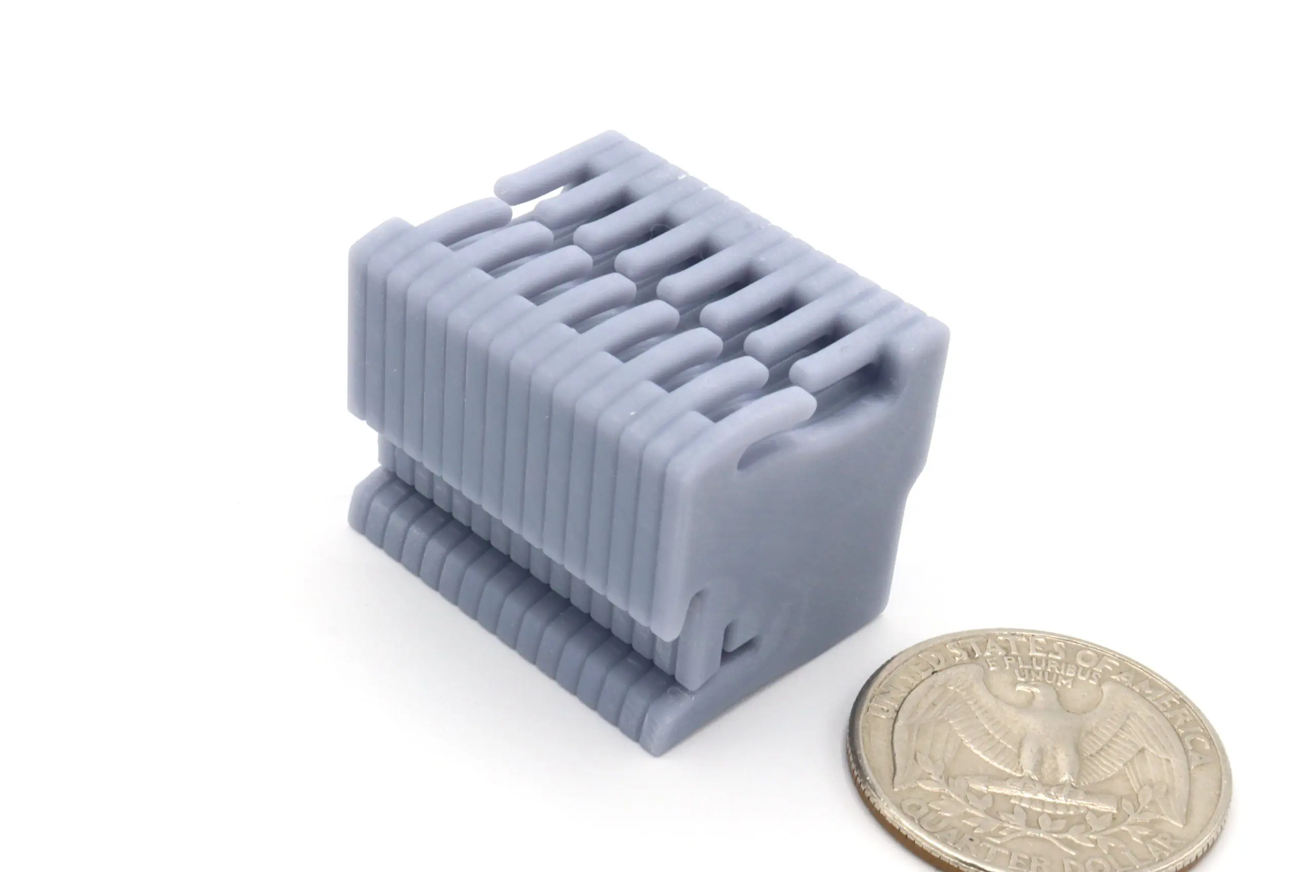 Gray 3D-printed object beside a coin.