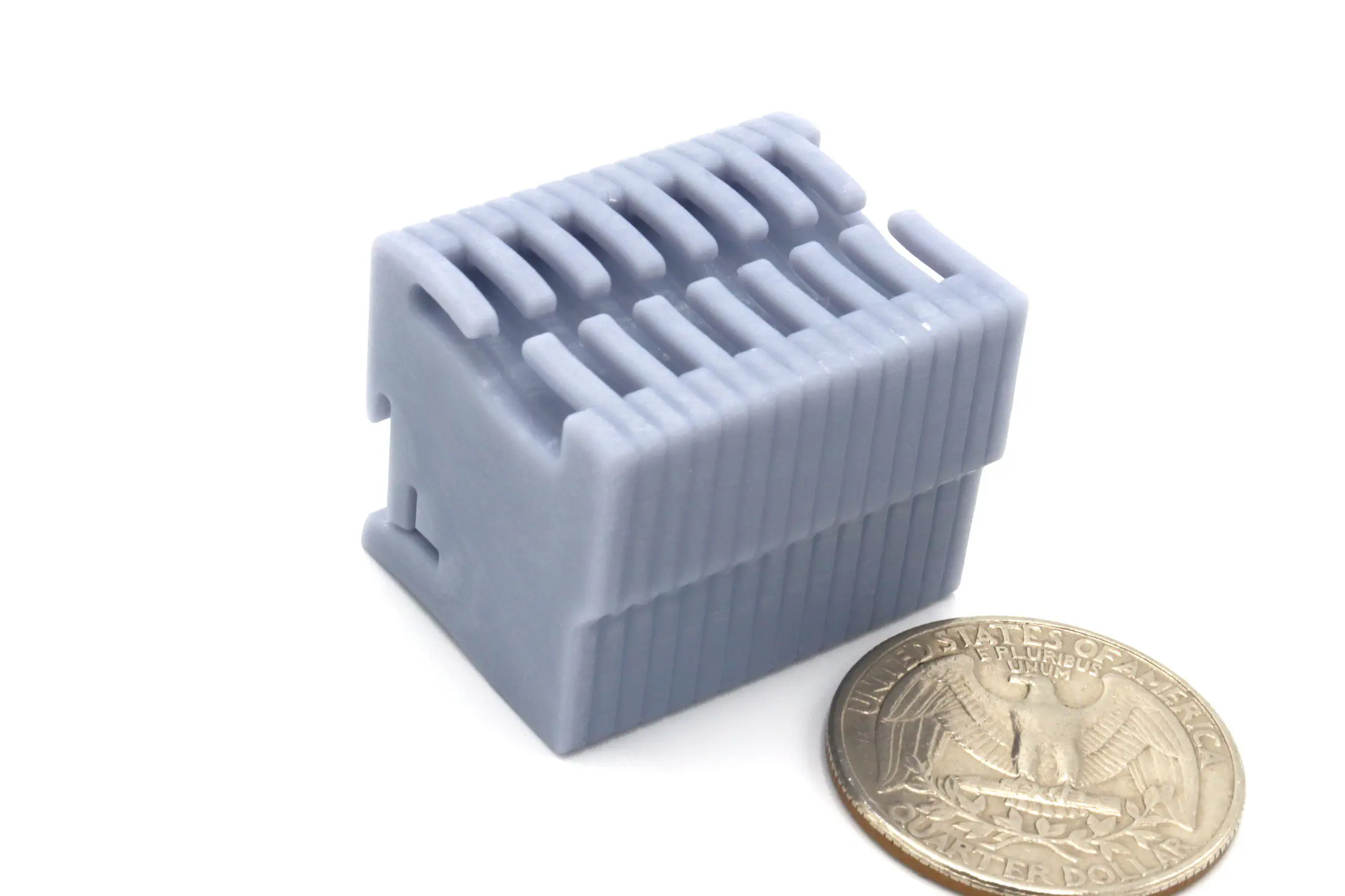 Gray plastic component beside a U.S. quarter.