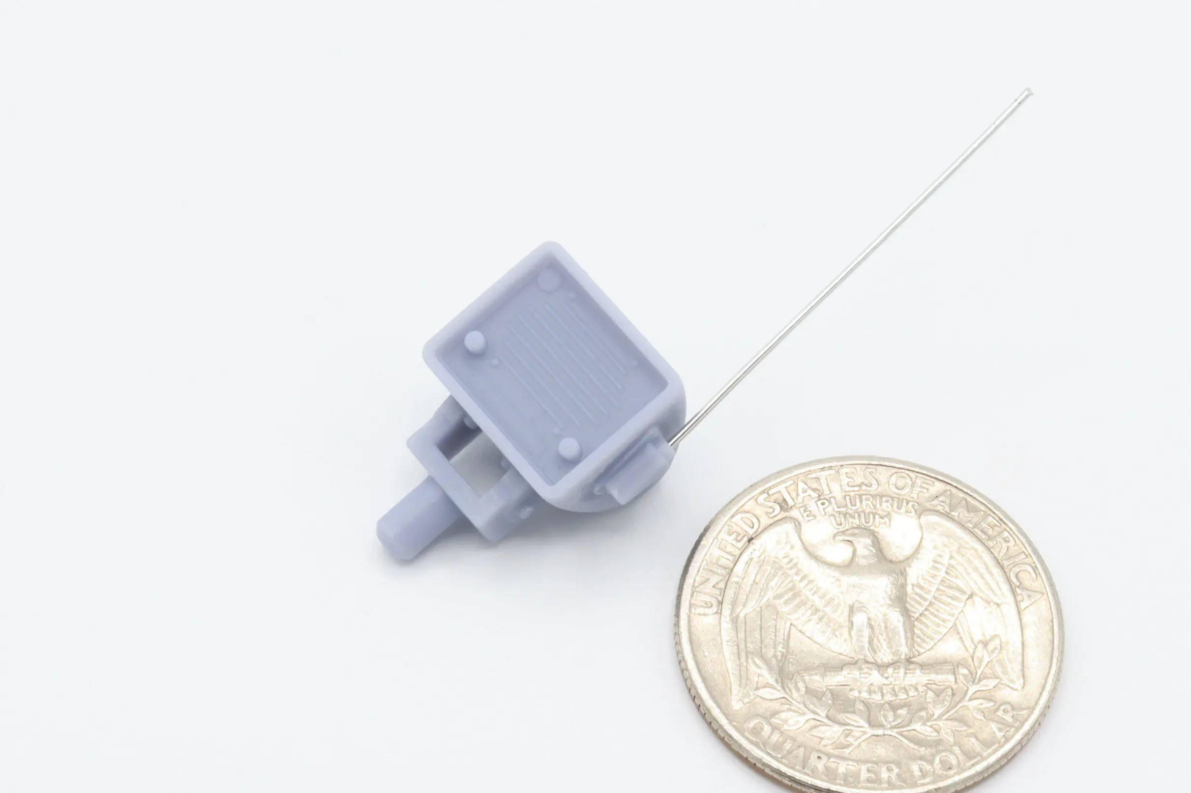 Small gray device next to a coin.