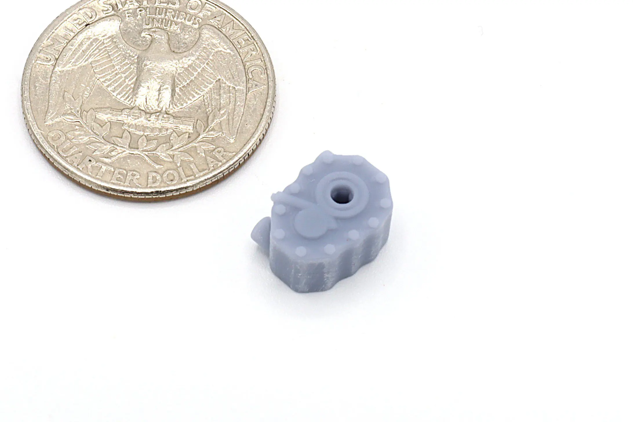 Small gray gear beside a quarter coin.