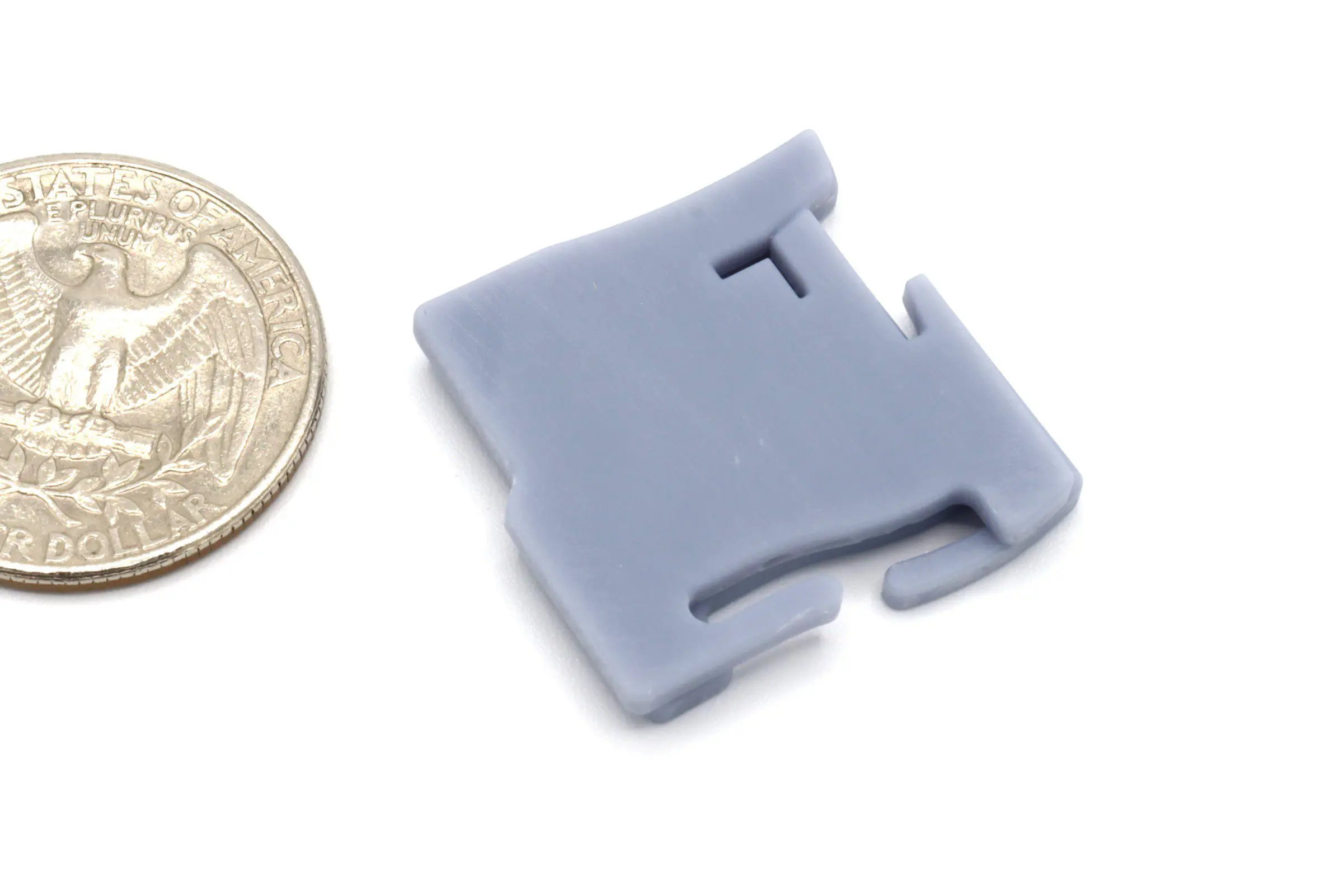 Gray plastic clip beside a quarter coin.