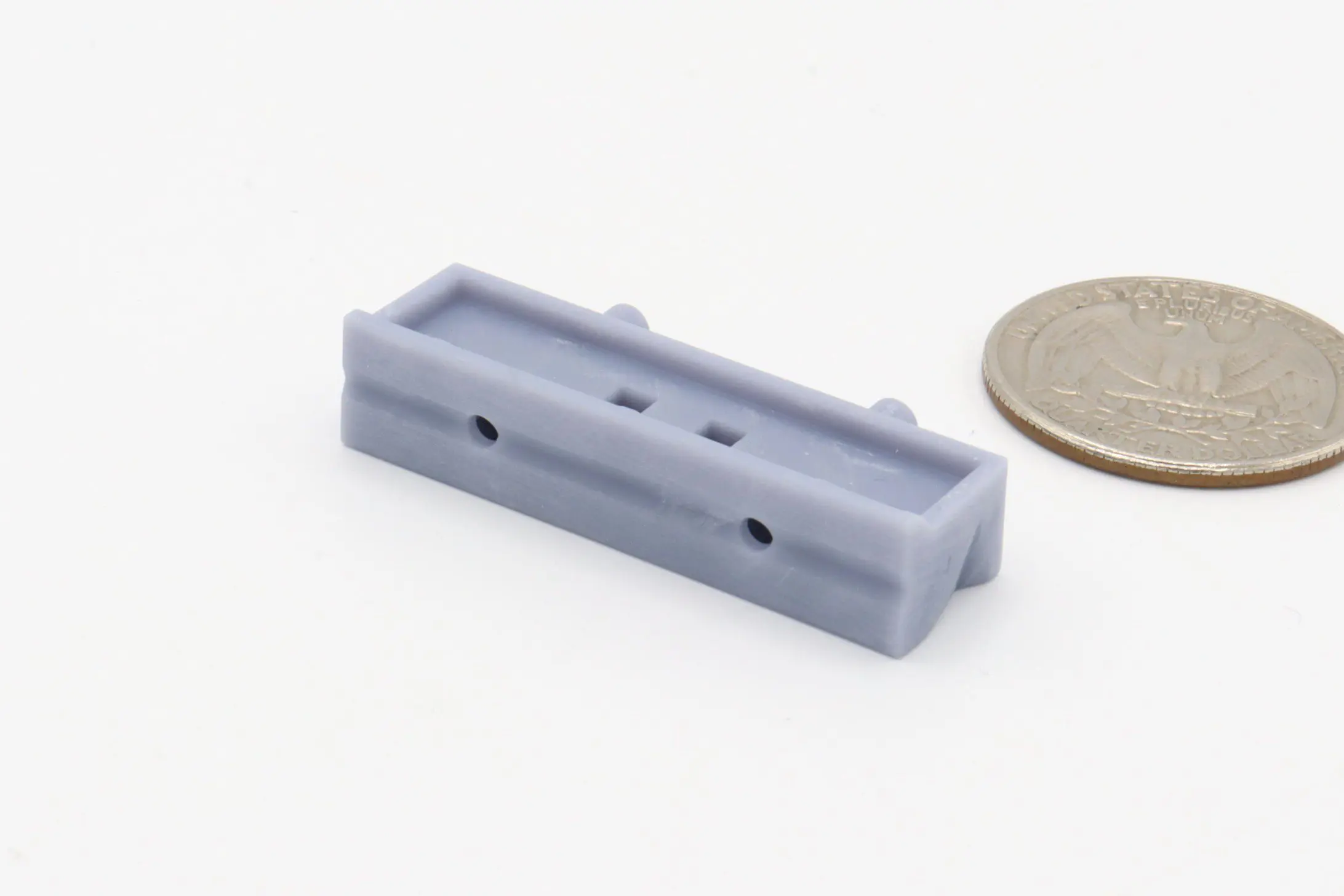 Gray plastic part beside a coin.
