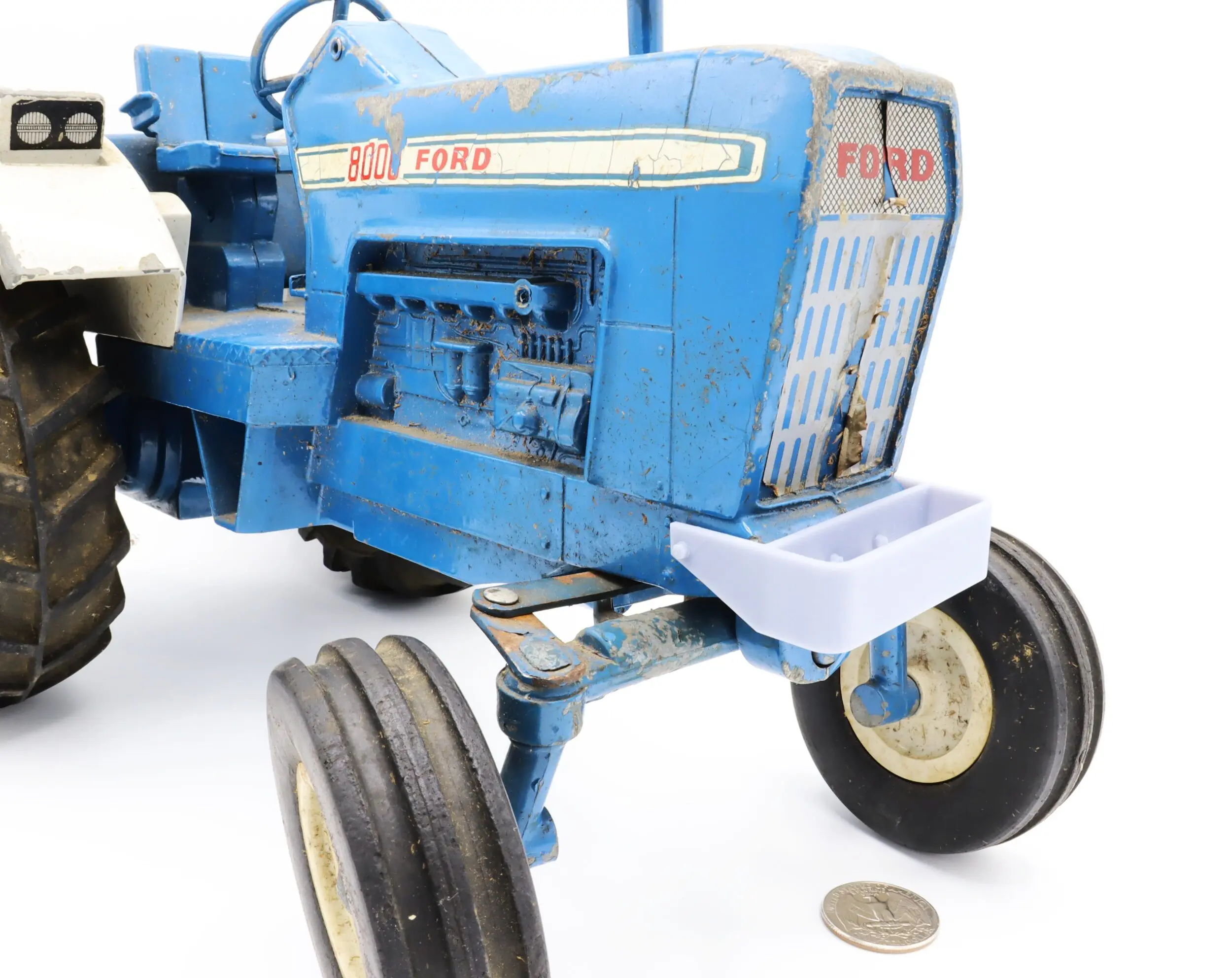 Blue Ford tractor model with coin nearby.