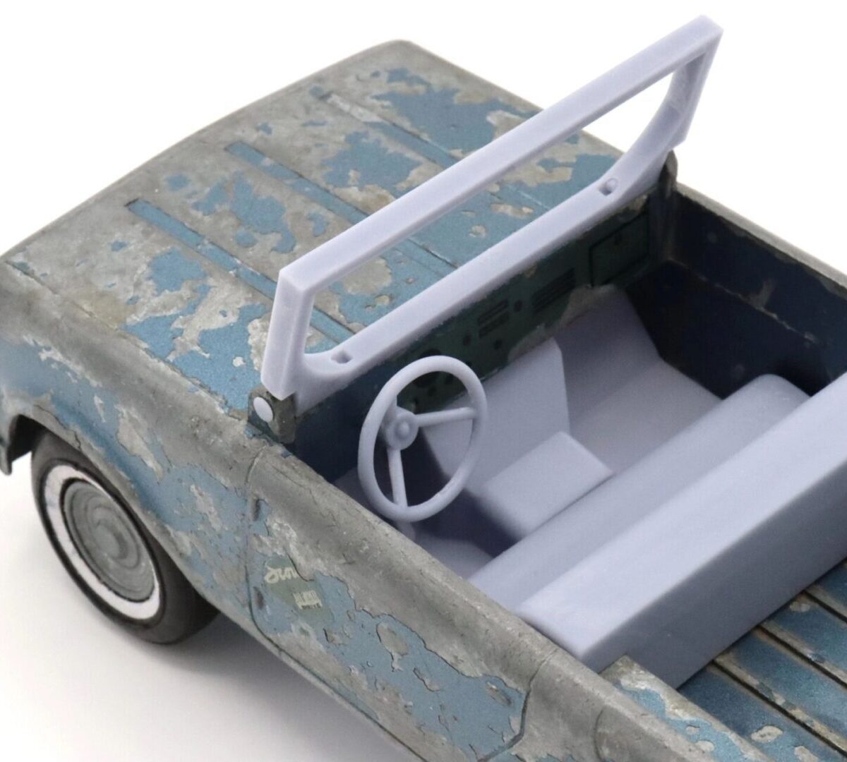 A weathered toy car with a white steering wheel and seats.