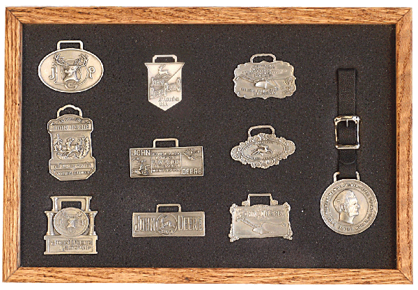 A collection of antique silver charms displayed in a wooden case.