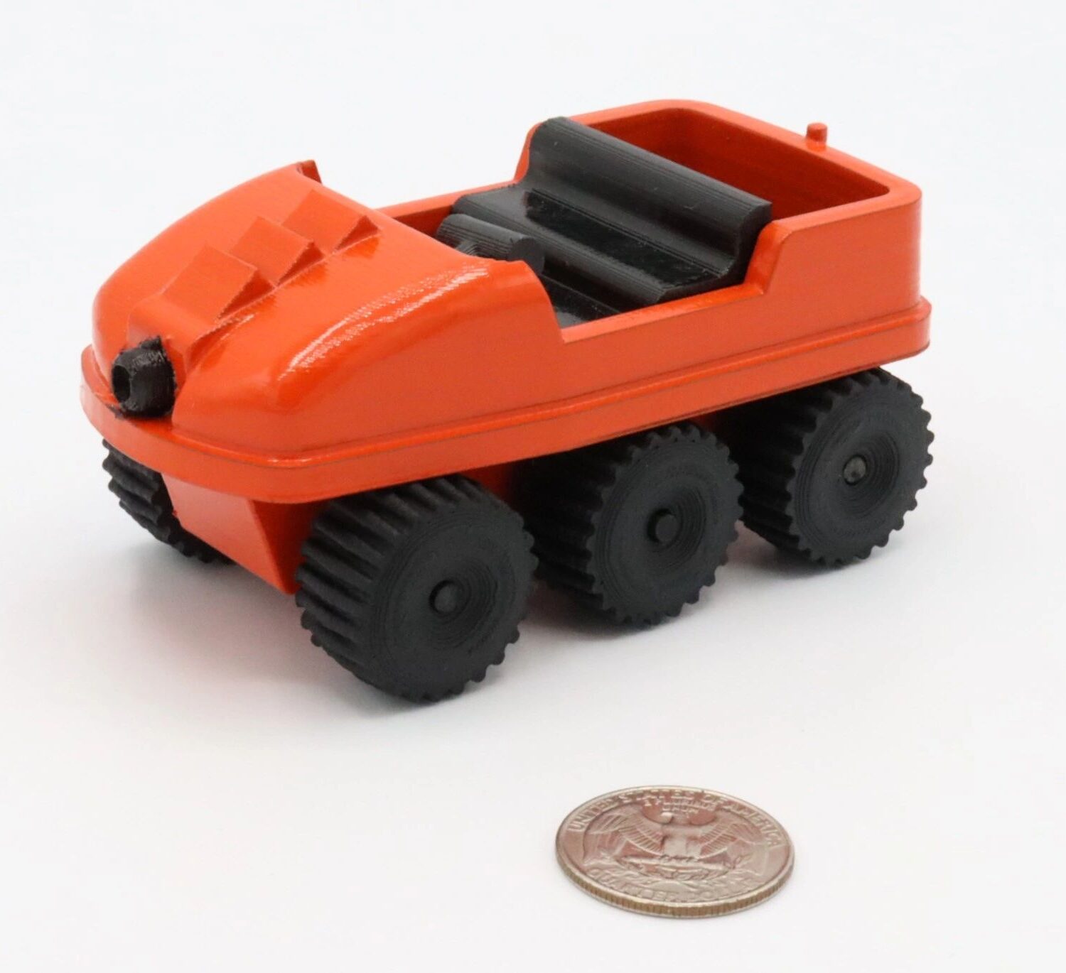 Small orange toy vehicle with six black wheels beside a coin.