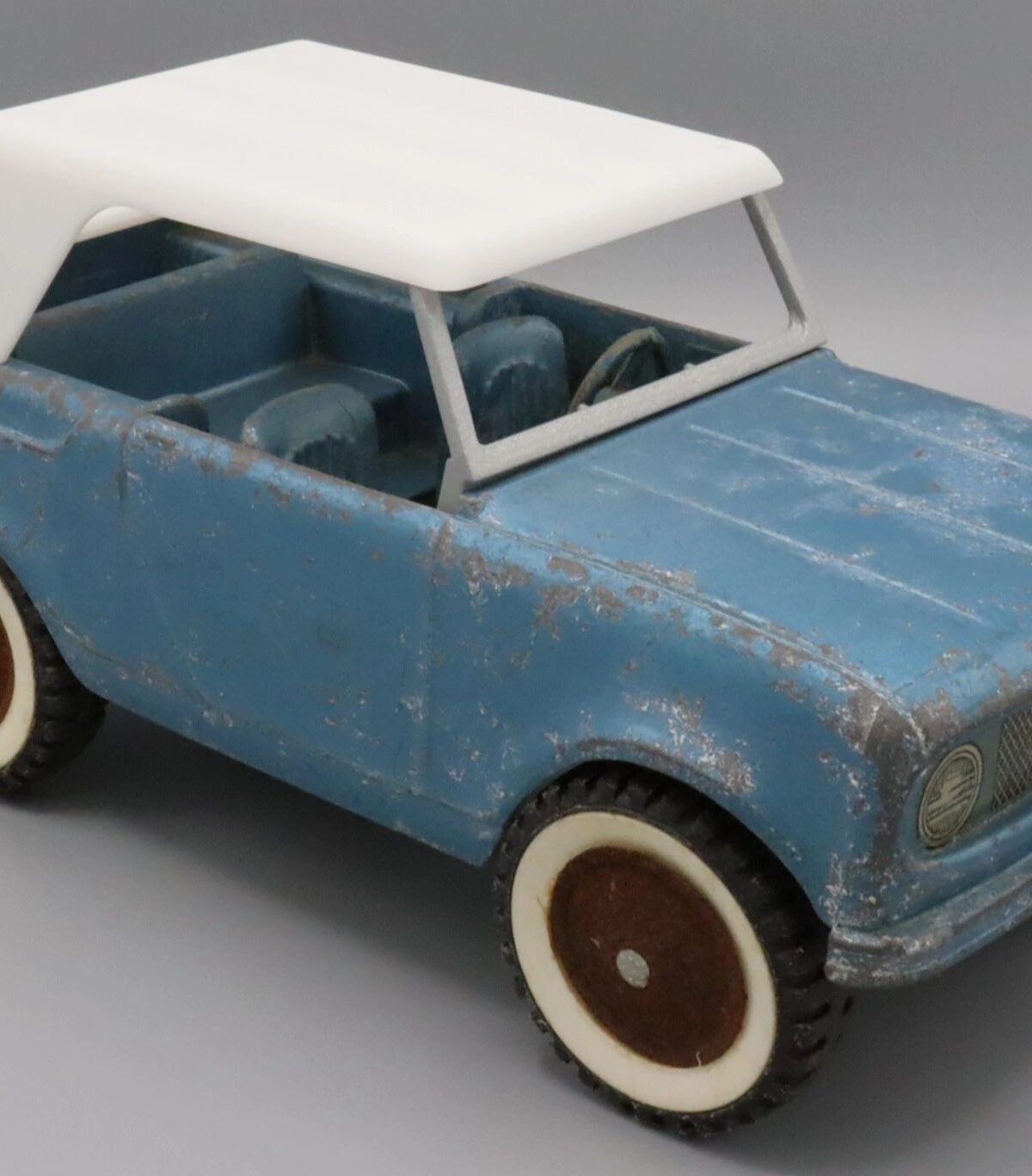 Vintage blue toy car with a white roof and brown wheels.