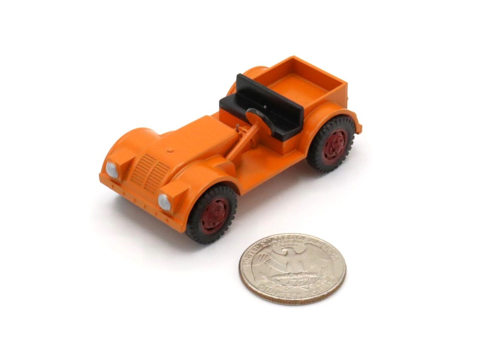 Small orange toy car beside a coin for scale.