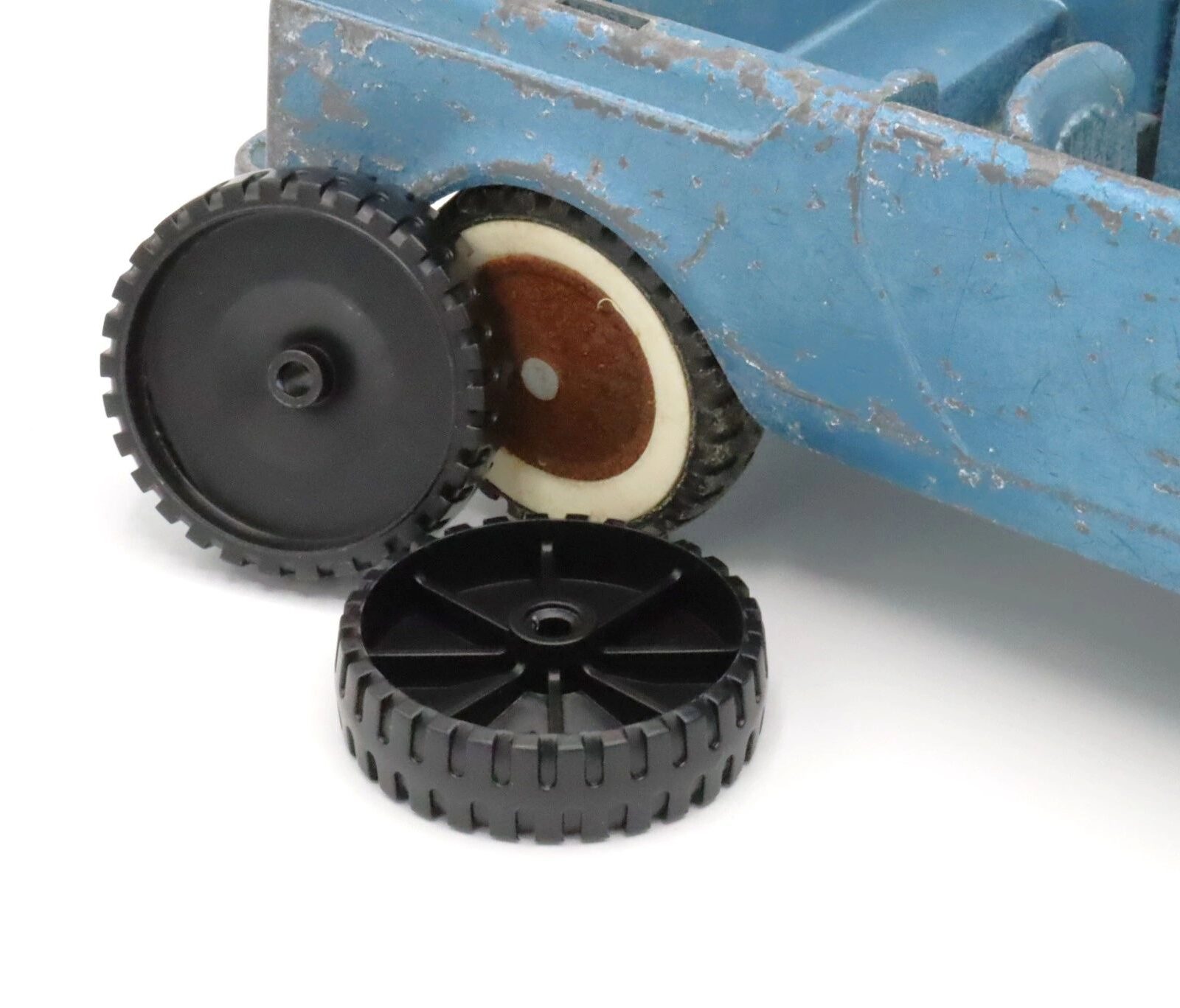 Three detached toy wheels placed next to a blue toy vehicle.